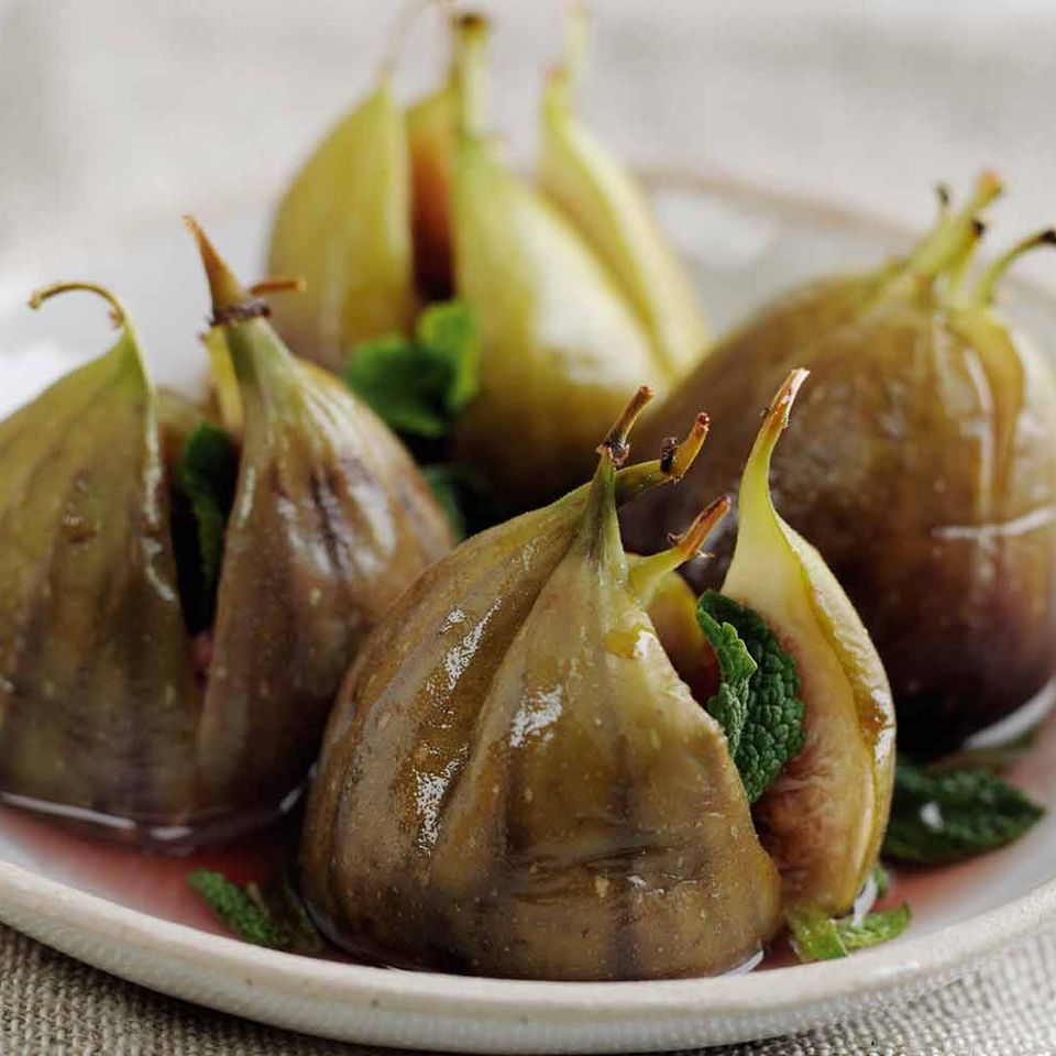 a white plate topped with stuffed figs and mint leaves on a table .