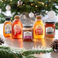 several bottles of rowse honey are on a table in front of a christmas tree