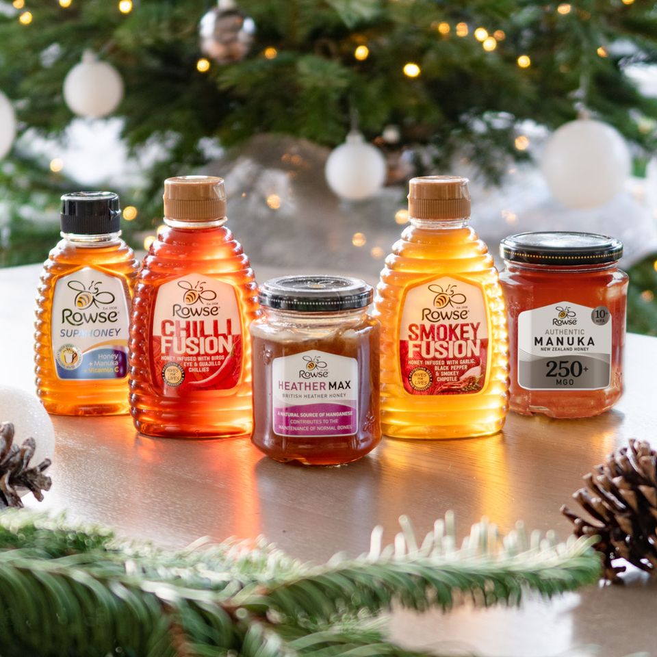 several bottles of rowse honey are on a table in front of a christmas tree