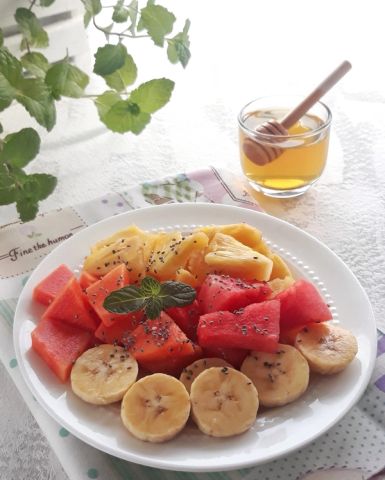 a plate of fruit and a jar of honey