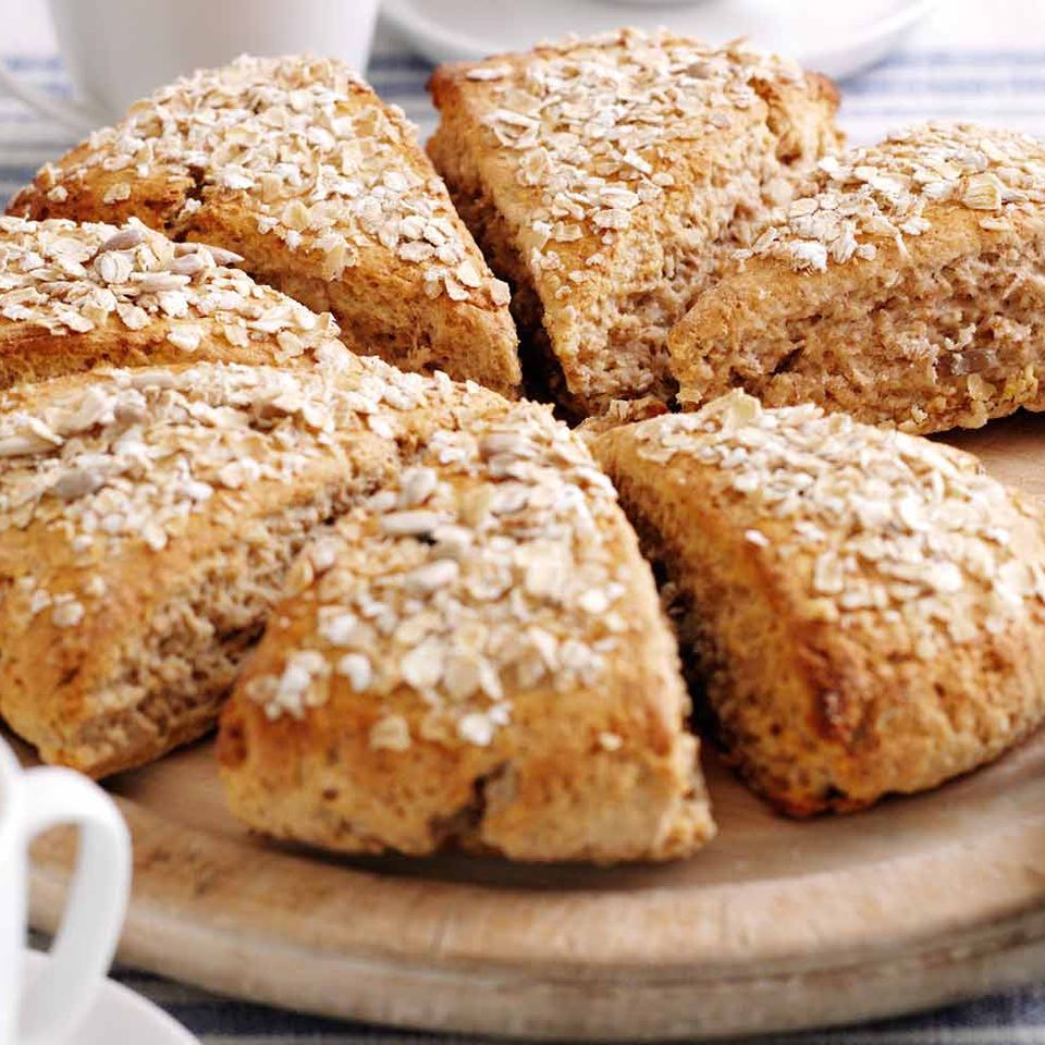 a wooden cutting board topped with oatmeal scones and a cup of coffee .