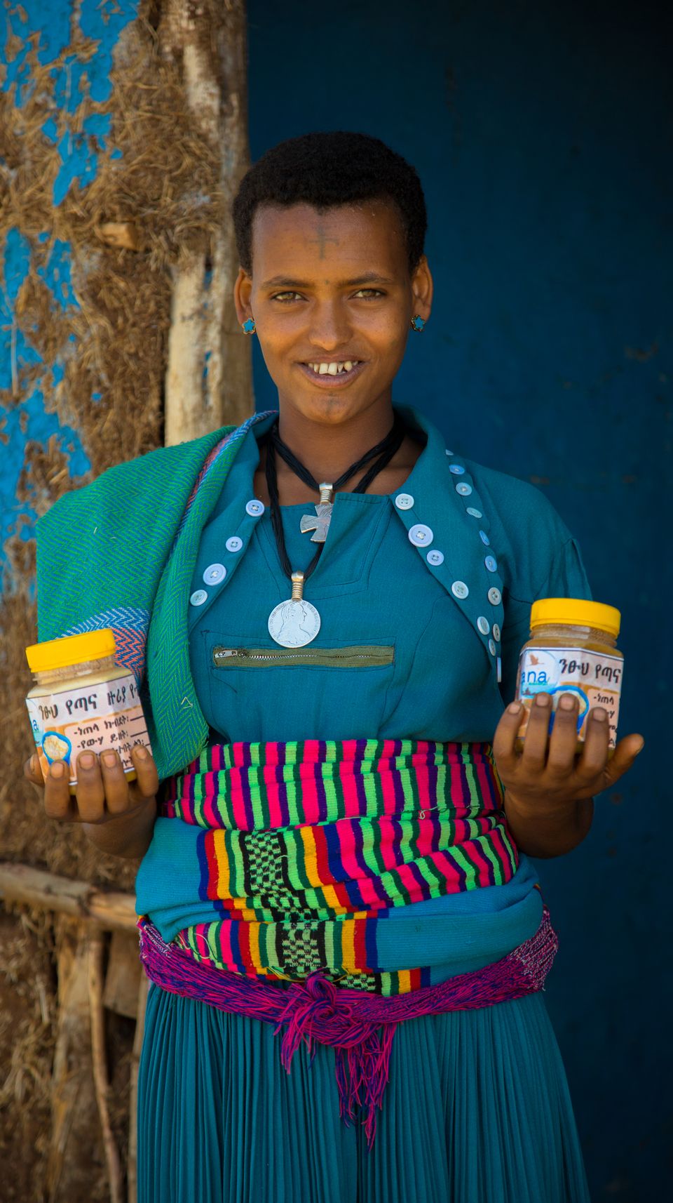 a woman in a blue dress is holding two jars of honey