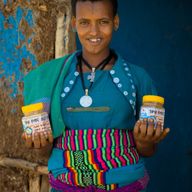 a woman in a blue dress is holding two jars of honey