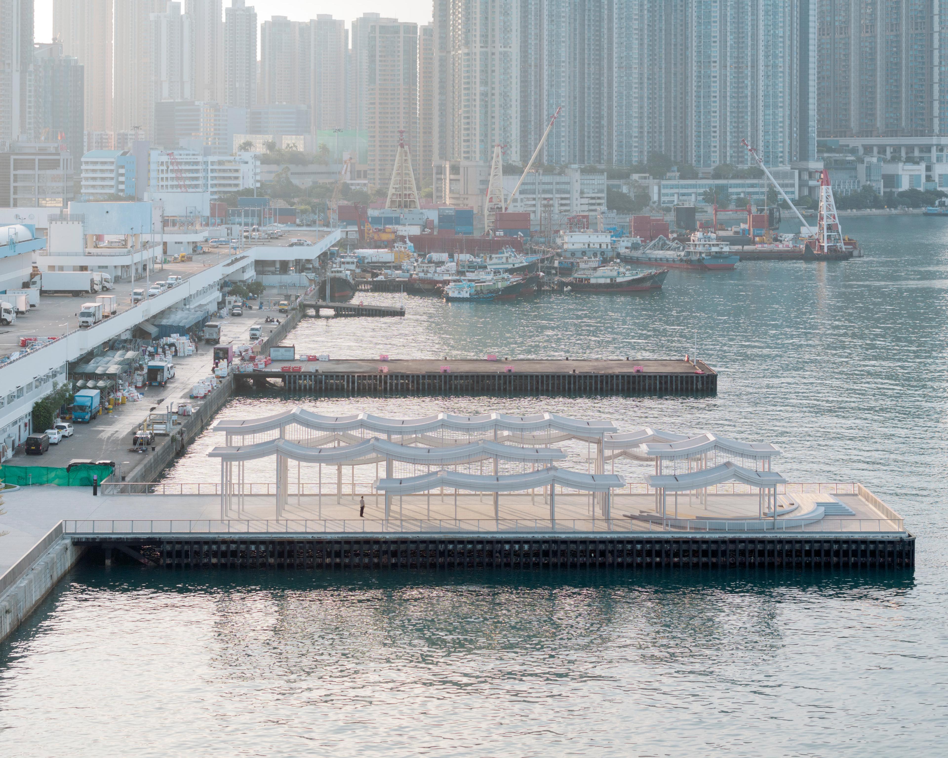 Aerial view of refurbished pier and undulating pier canopy along industrial waterfront