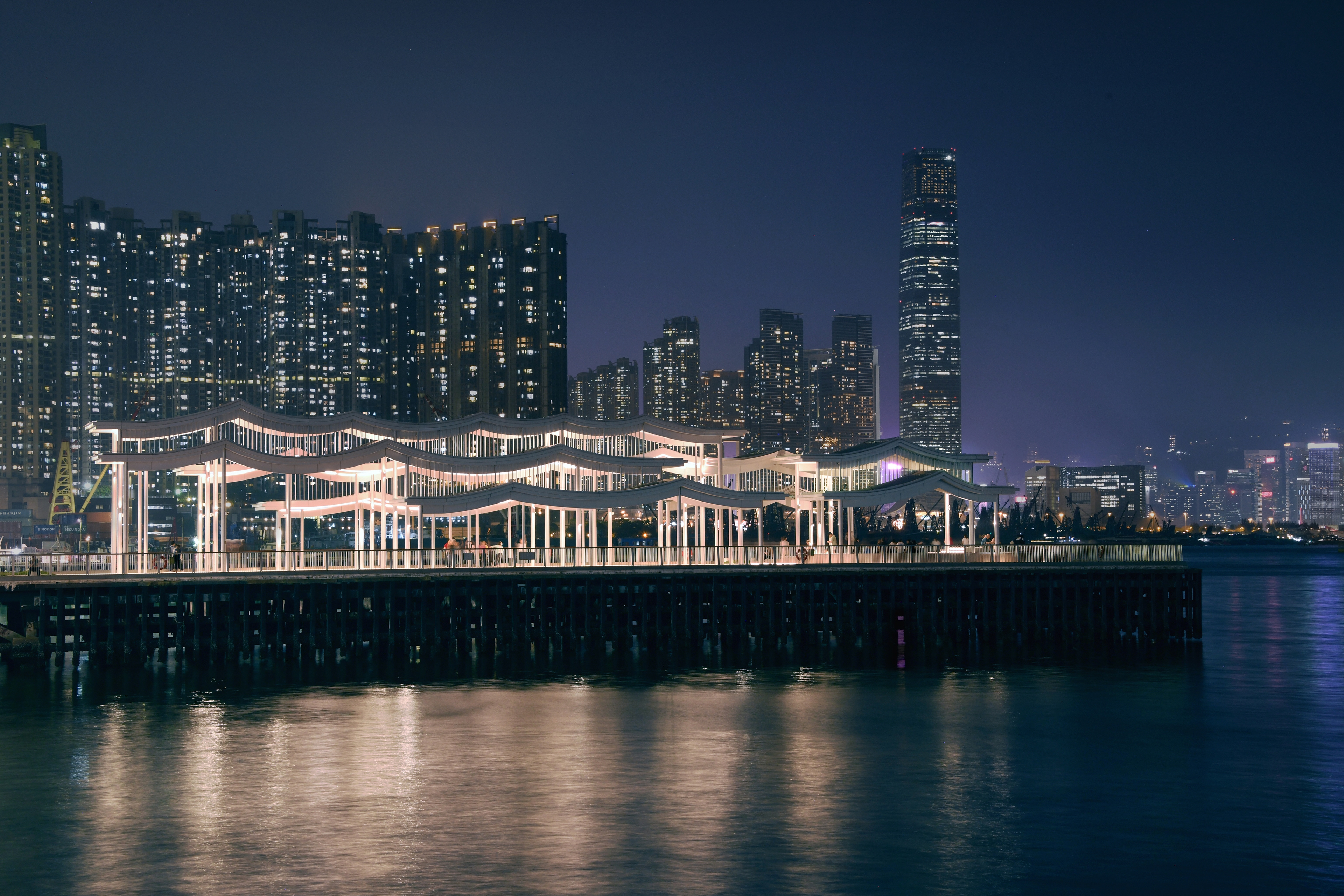 Pier with undulating canopy and Hong Kong skyline in background