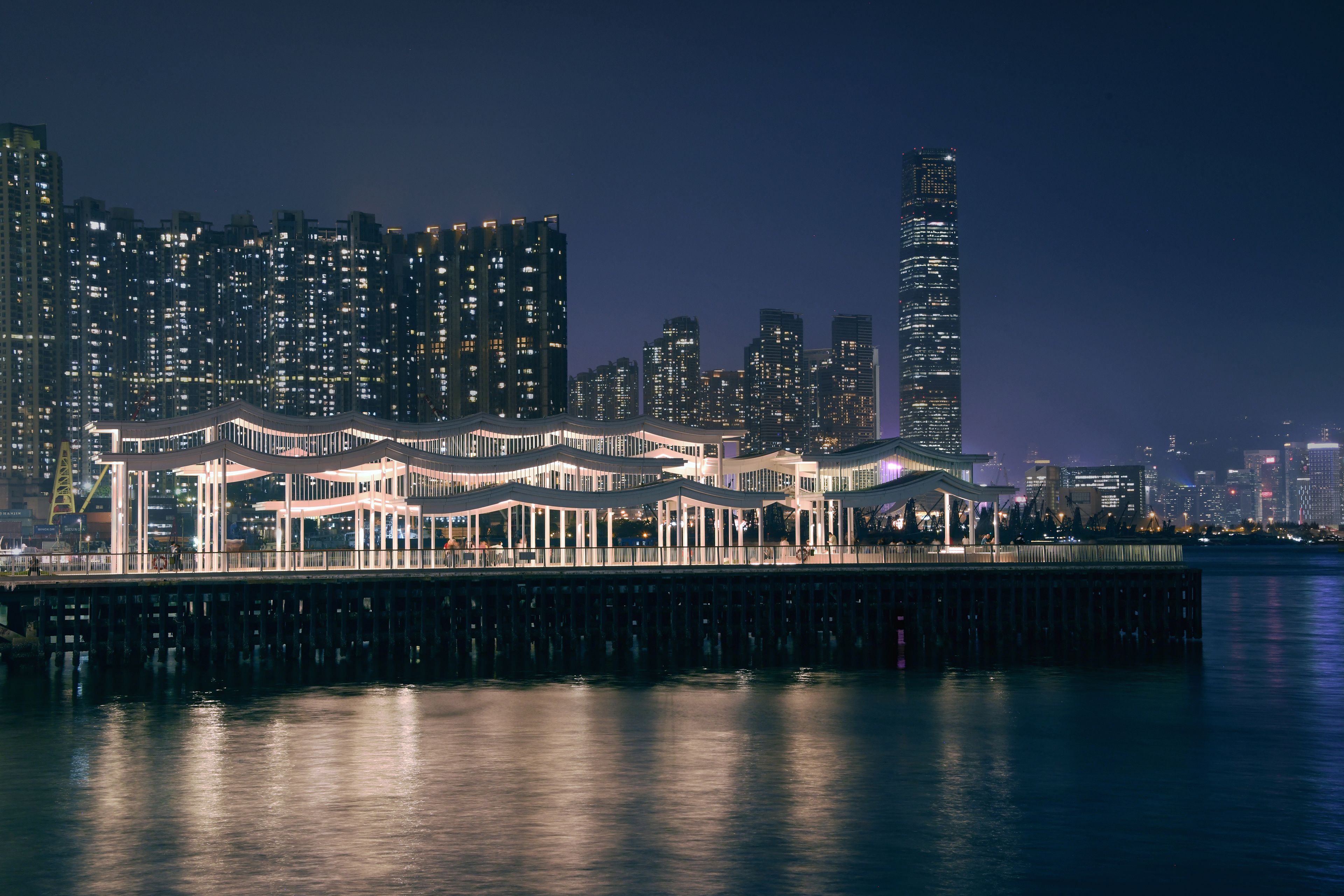 Pier with undulating canopy and Hong Kong skyline in background