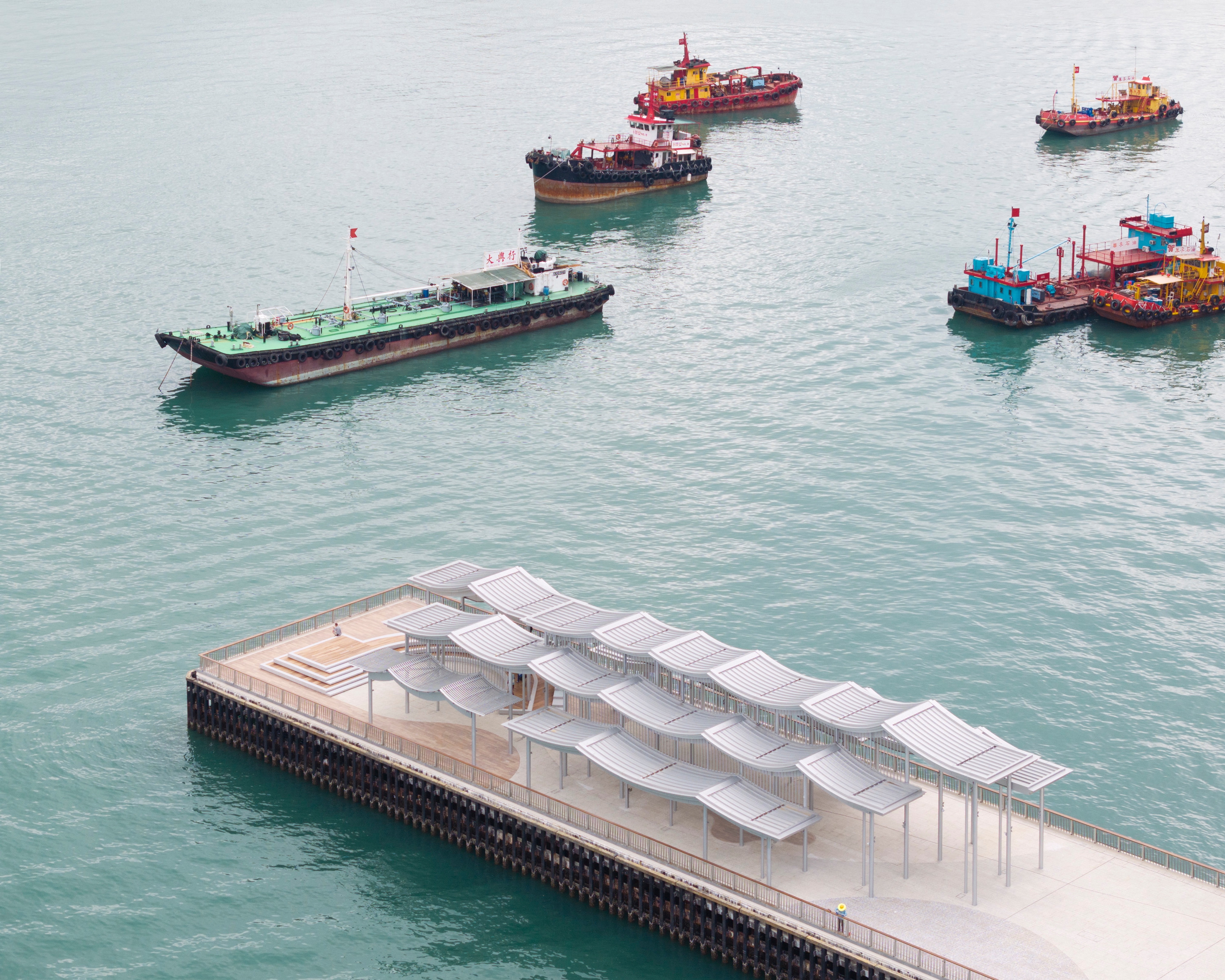 Undulating pier canopy with boats in the background