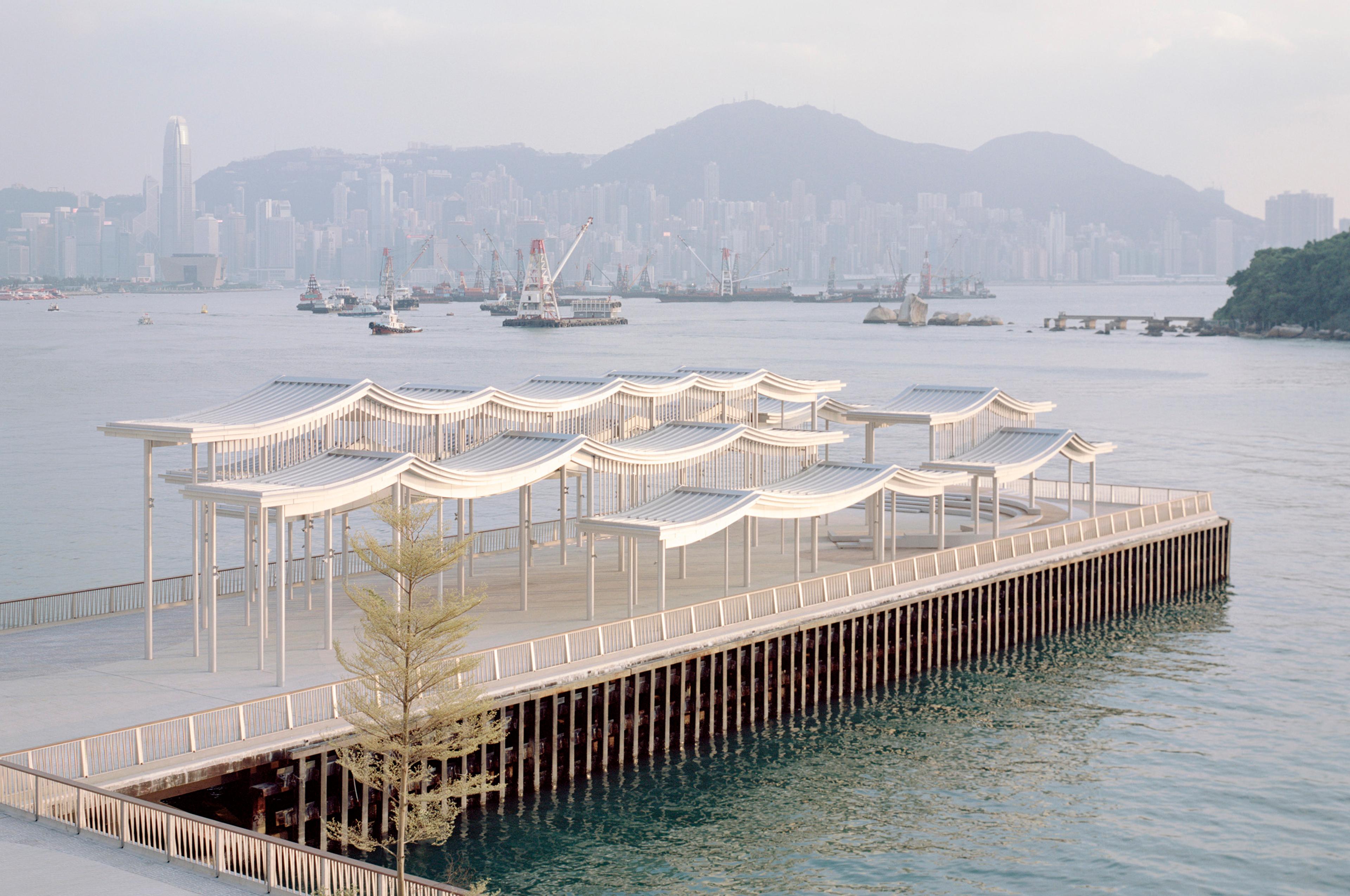 Pier with undulating canopy and Hong Kong skyline in background