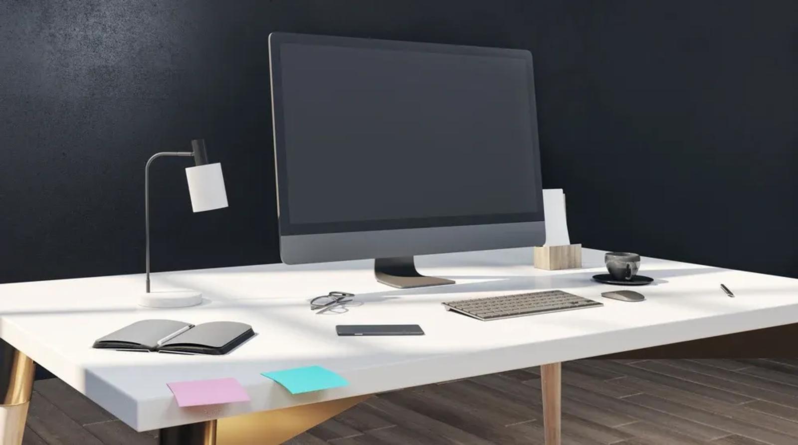 Clean modern office desk with monitor keyboard and lamp representing a professional google ad copy tool workflow