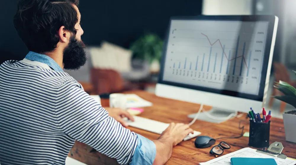 Digital marketing specialist analyzing Google Ads campaign performance on large monitor