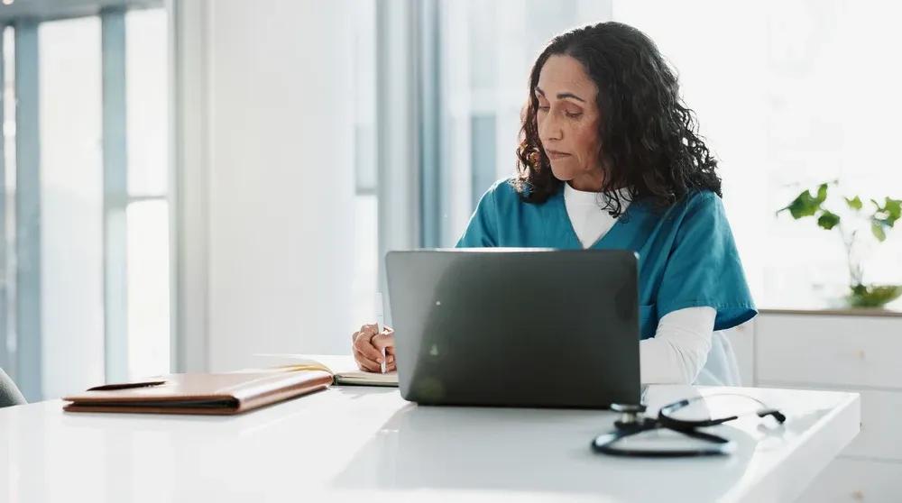 Healthcare professional reviewing patient data on a laptop representing local SEO for healthcare clinics