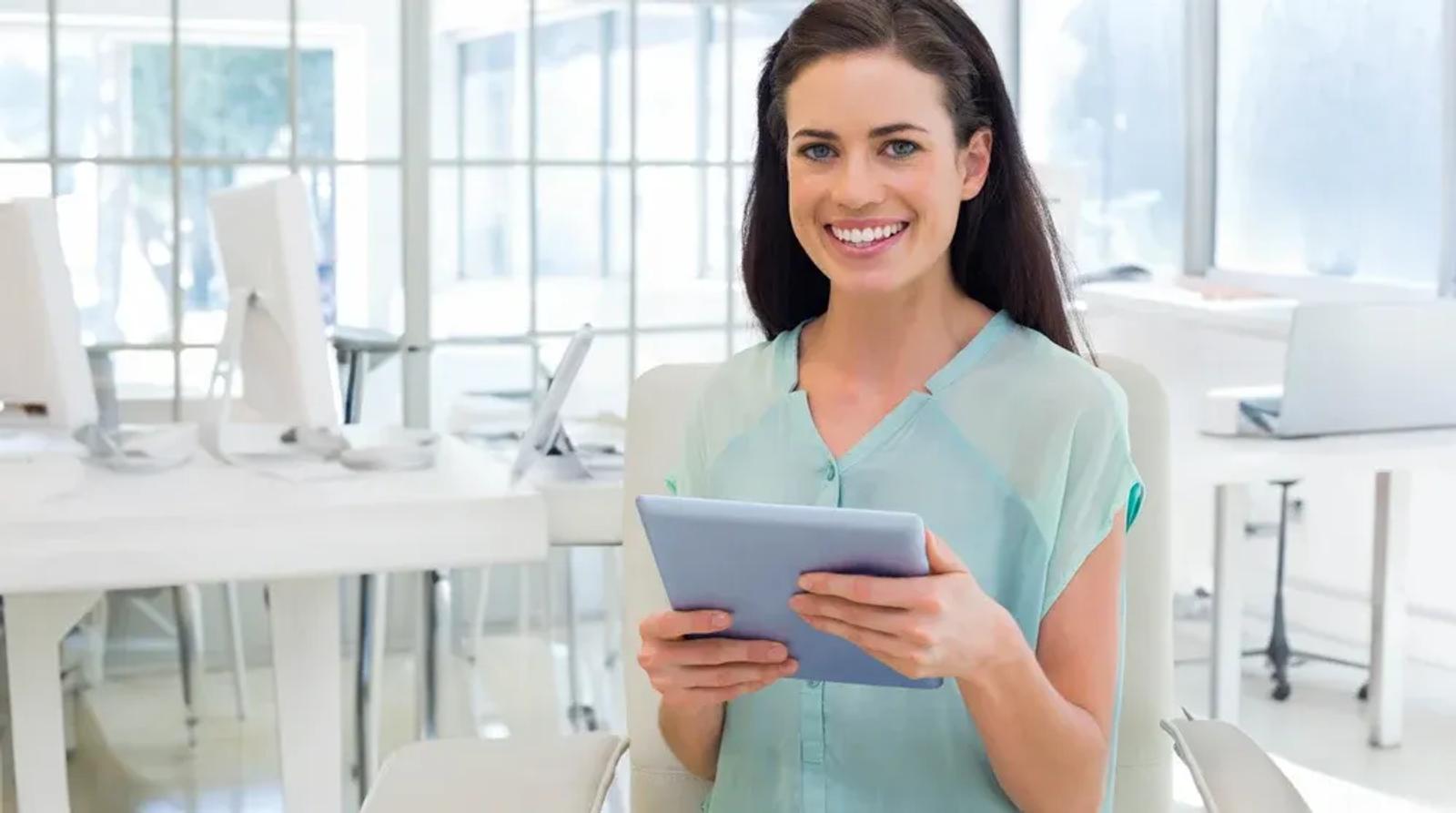 Dental receptionist managing Google Business Profile on tablet at modern dental clinic reception