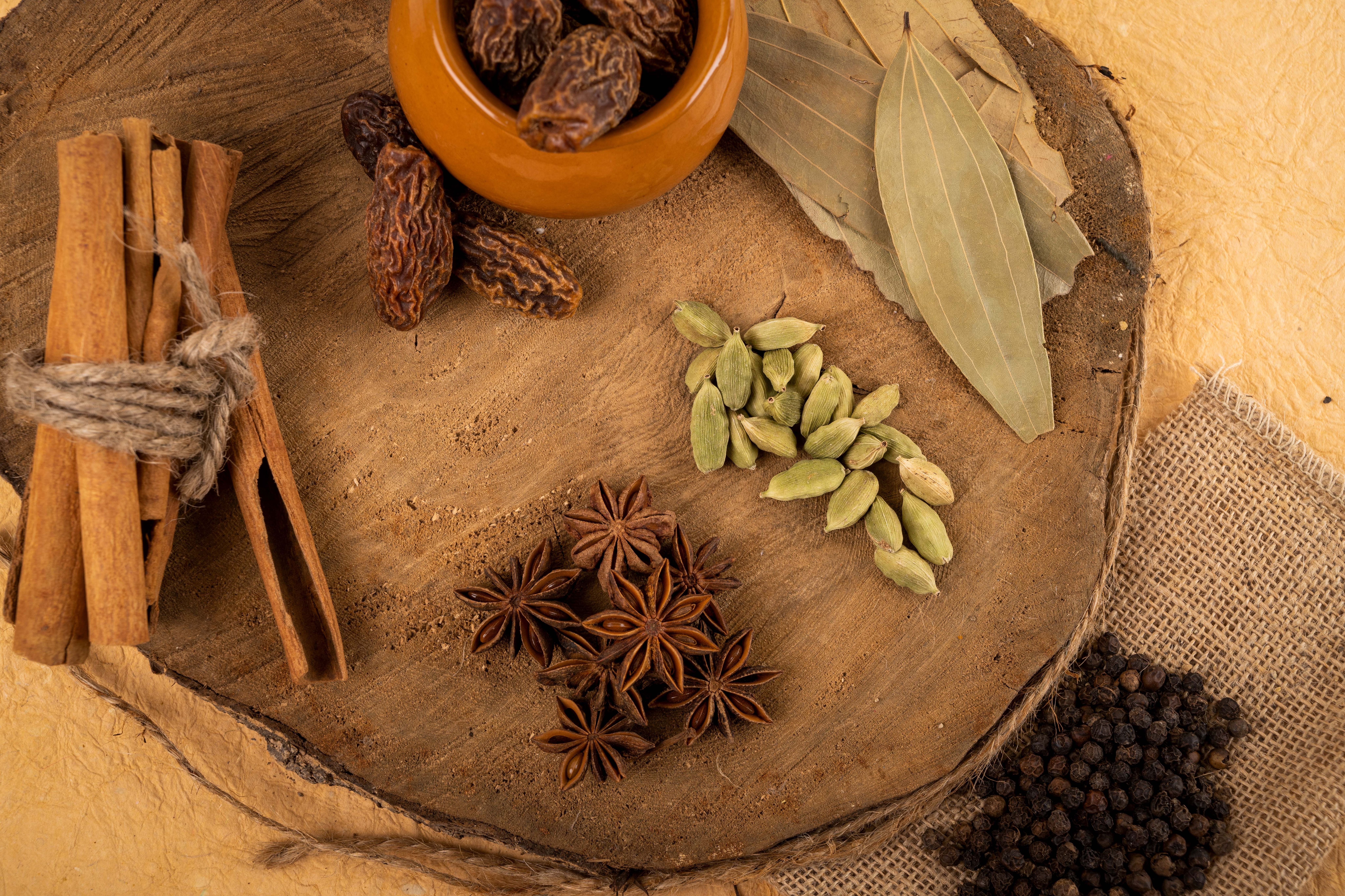 Cinnamon sticks, cardamom, star anise, bay leaves and peppercorns on a wooden board