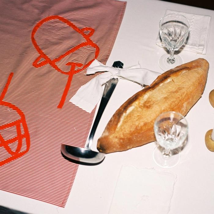 Festa, premier repas autour du keşkek, 14 septembre 2023, Marseille, détail : table, nappe brodée avec des rubans en velours, ustensiles, pain et bougies © Emma Tholot