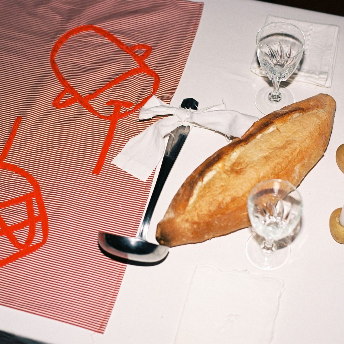 Festa, premier repas autour du keşkek, 14 septembre 2023, Marseille, détail : table, nappe brodée avec des rubans en velours, ustensiles, pain et bougies © Emma Tholot