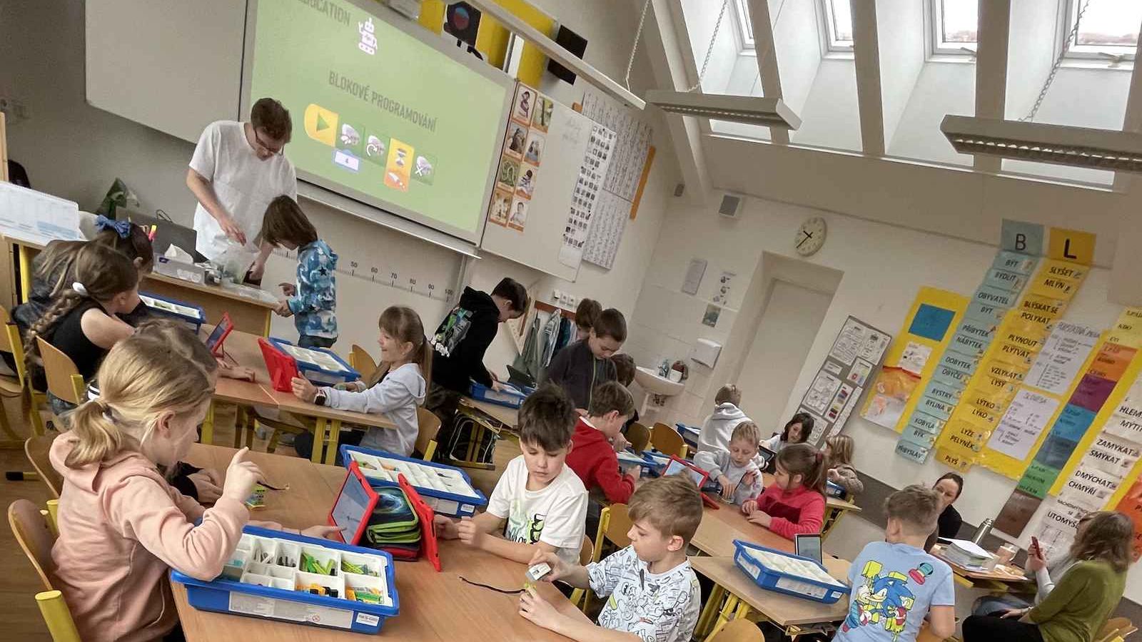 Lekce robotiky Robokids ve školní třídě, děti staví LEGO roboty ve dvojicích