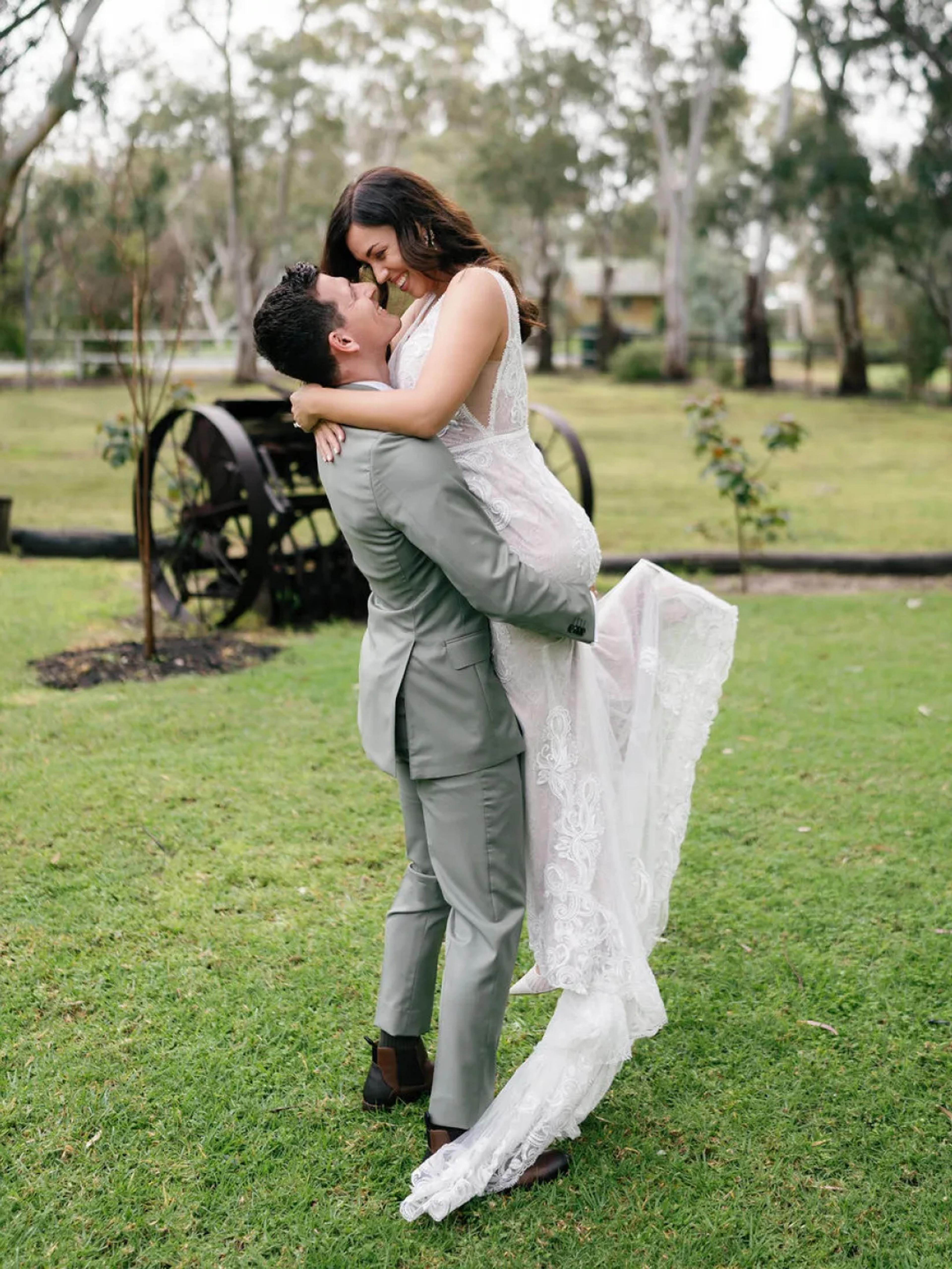 A photo of a married couple, the woman is jumping into the arms of the man.
