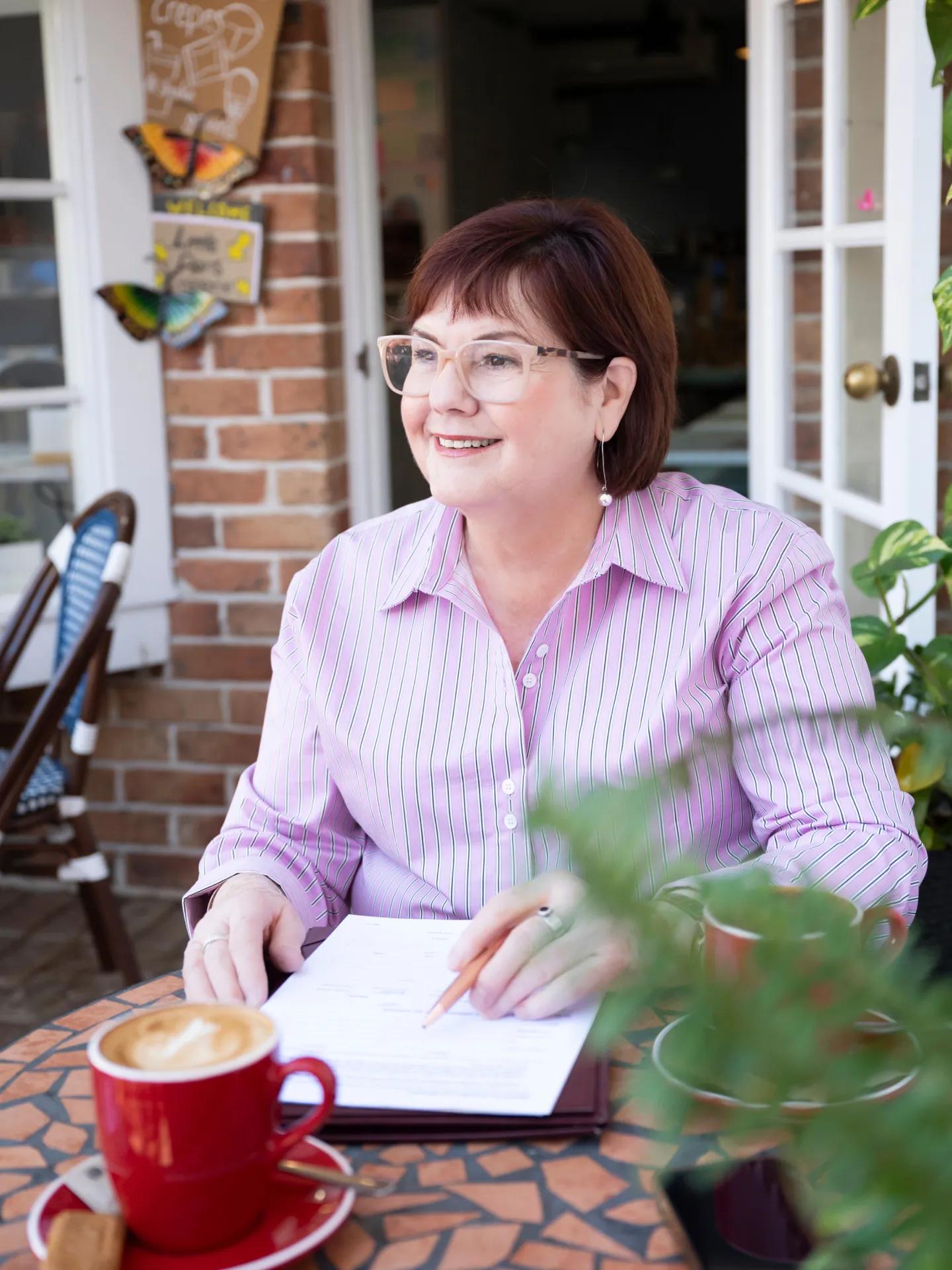 A photo of Jill Venn with a notebook and a coffee.