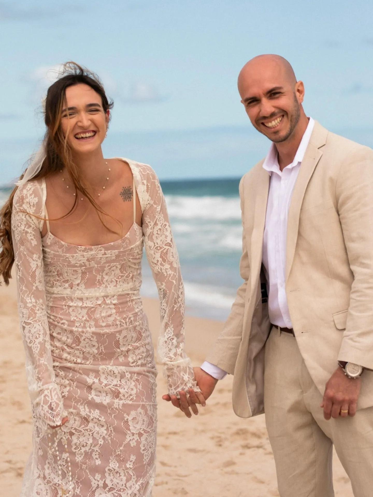 A photo of a couple holding hands on the beach.