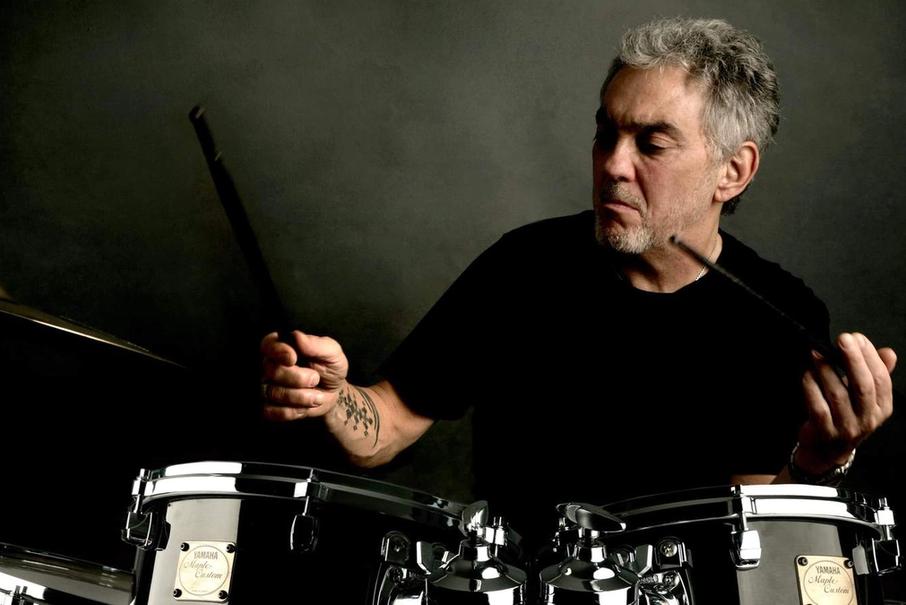 Un homme aux cheveux gris jouant de la batterie en prise traditionnelle