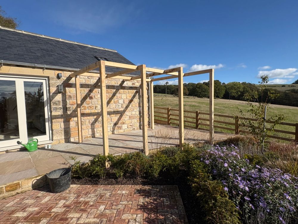 Contemporary oak pergola built against a stone house exterior in Harrogate by D&A Building & Landscaping
