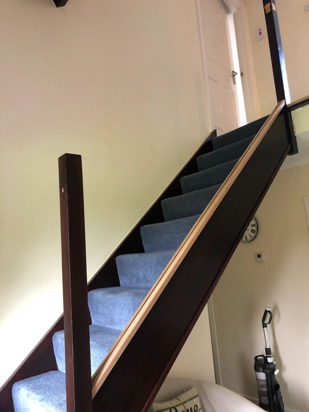 Carpeted staircase with dark wood frame and handrail ascending towards an upper floor doorway.