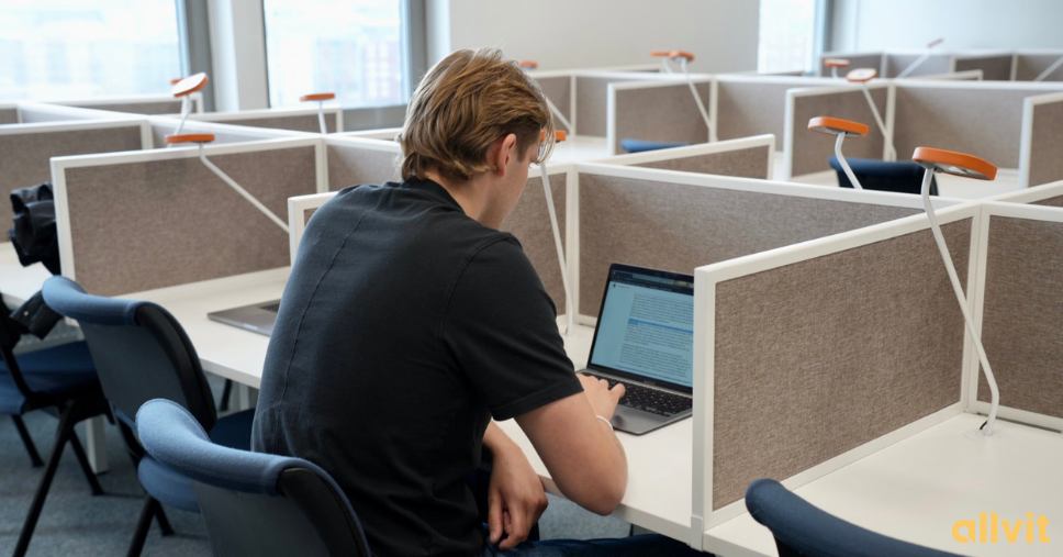 Gutt på lesesal med PC foran seg. Foto.