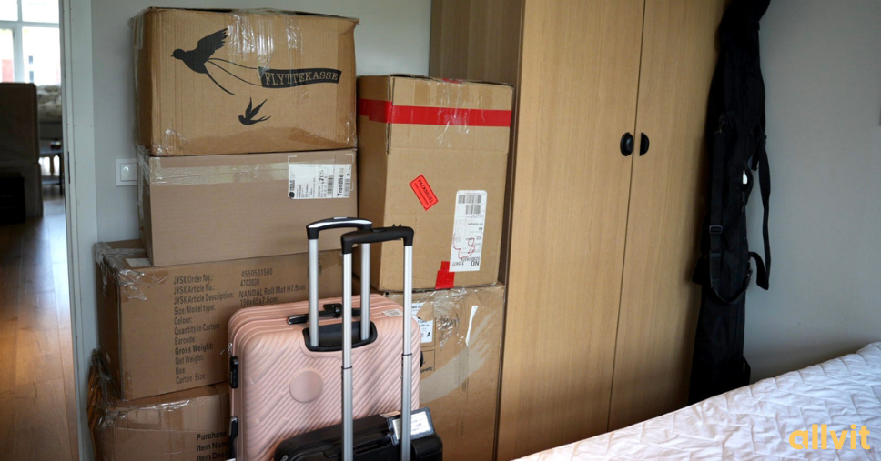 Flytteesker som står stablet med kofferter foran på et soverom. Foto.