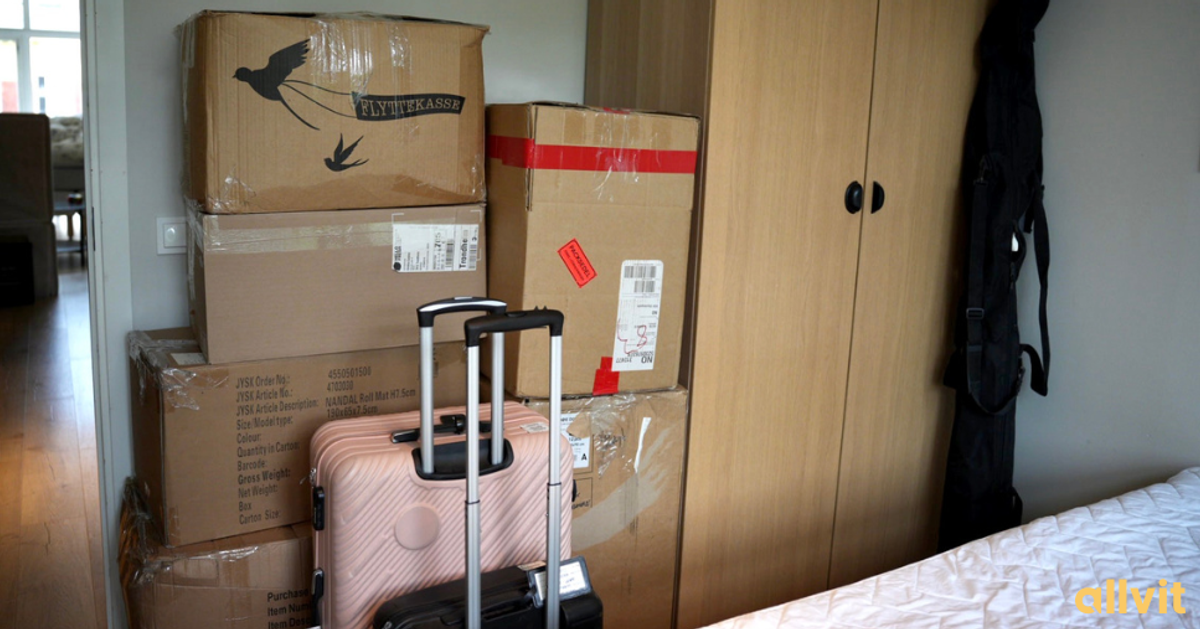 Flytteesker som står stablet med kofferter foran på et soverom. Foto.