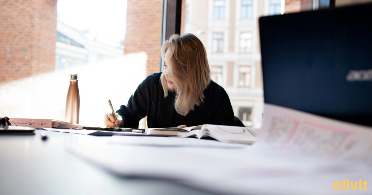 Jente som skriver i boka si på campus. Foto.