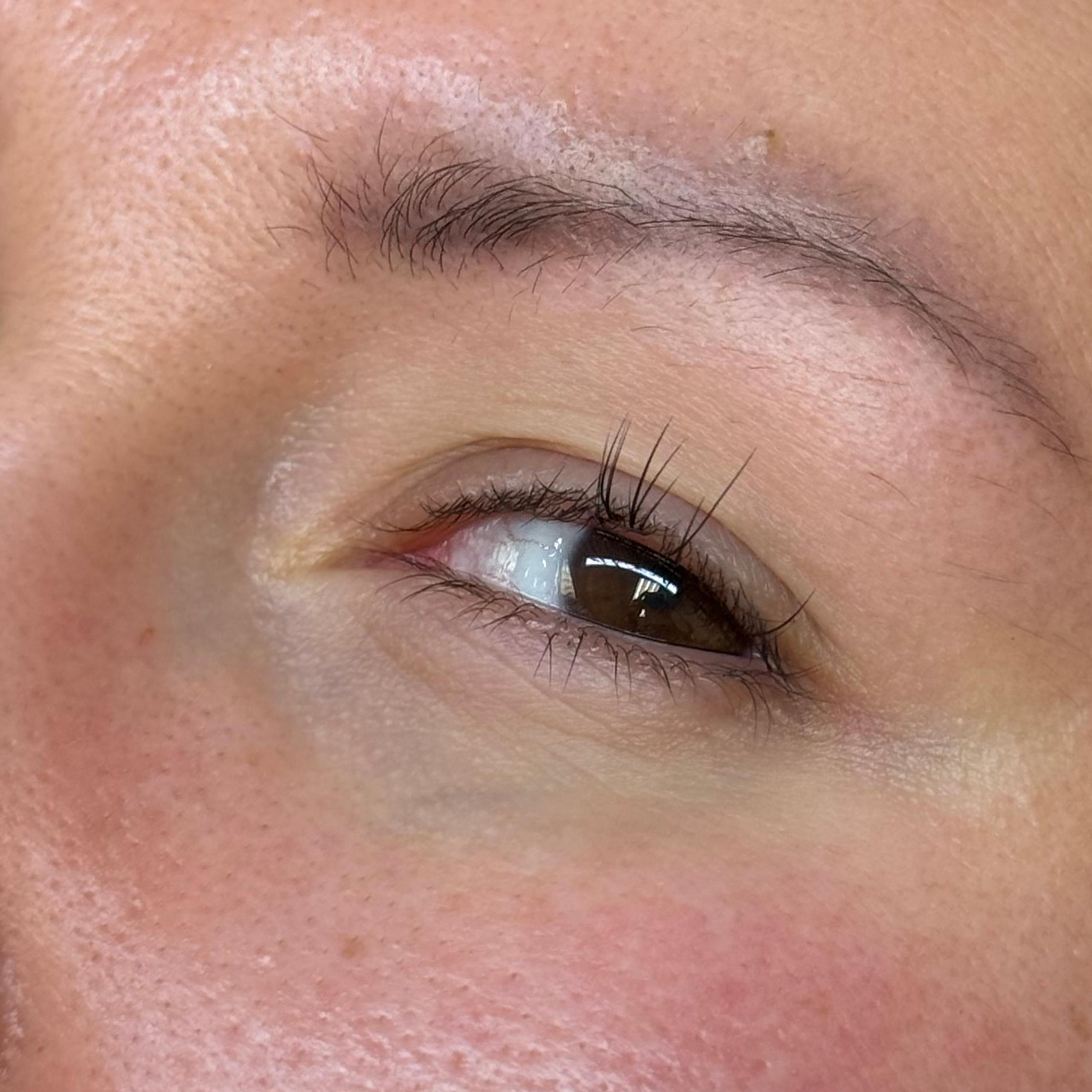 Close-up of a person's right eye with natural lashes wearing a white earbud.