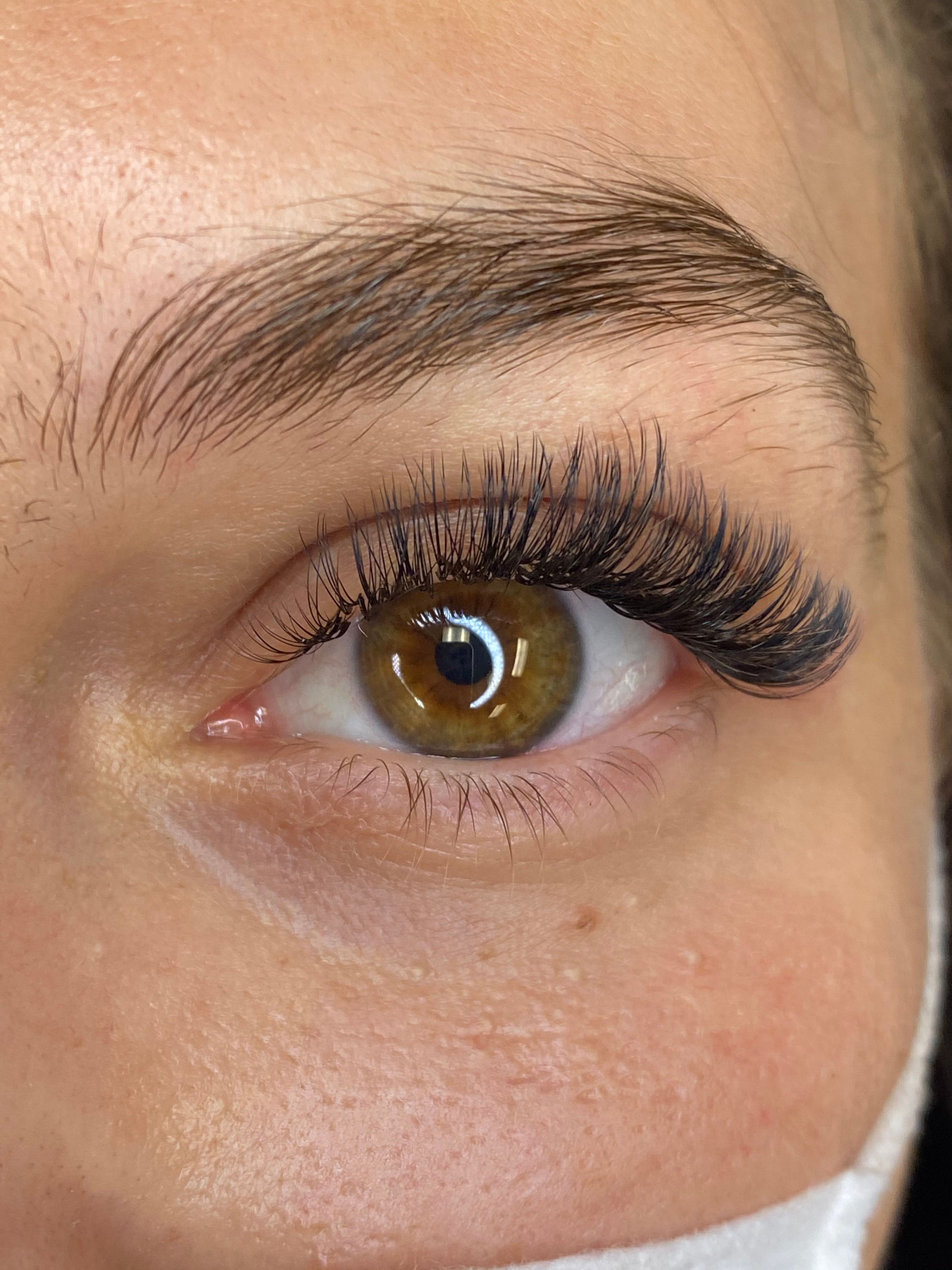 Close-up of a brown eye with dark, voluminous eyelash extensions.