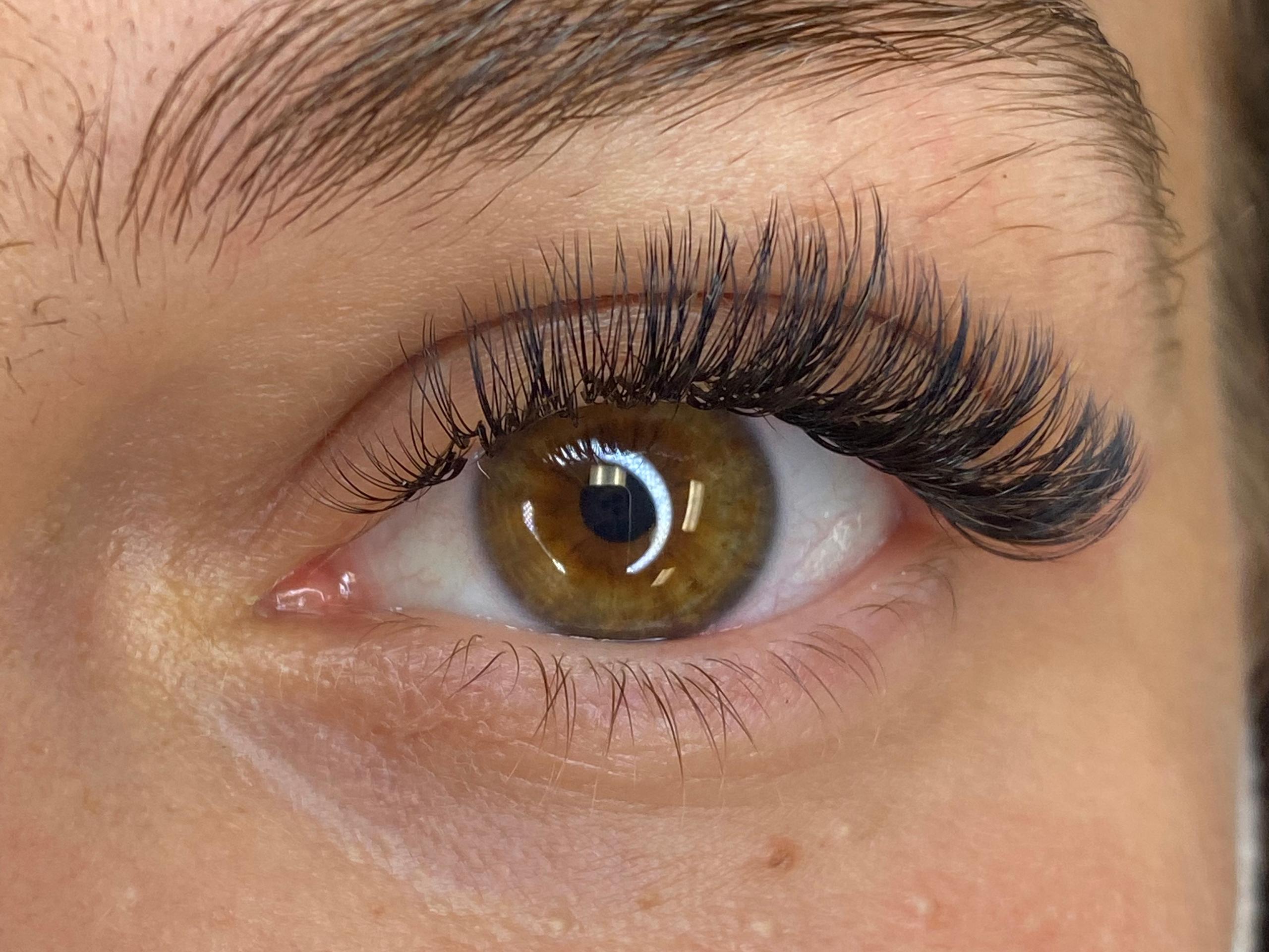 Close-up of a brown eye with dark, voluminous eyelash extensions.