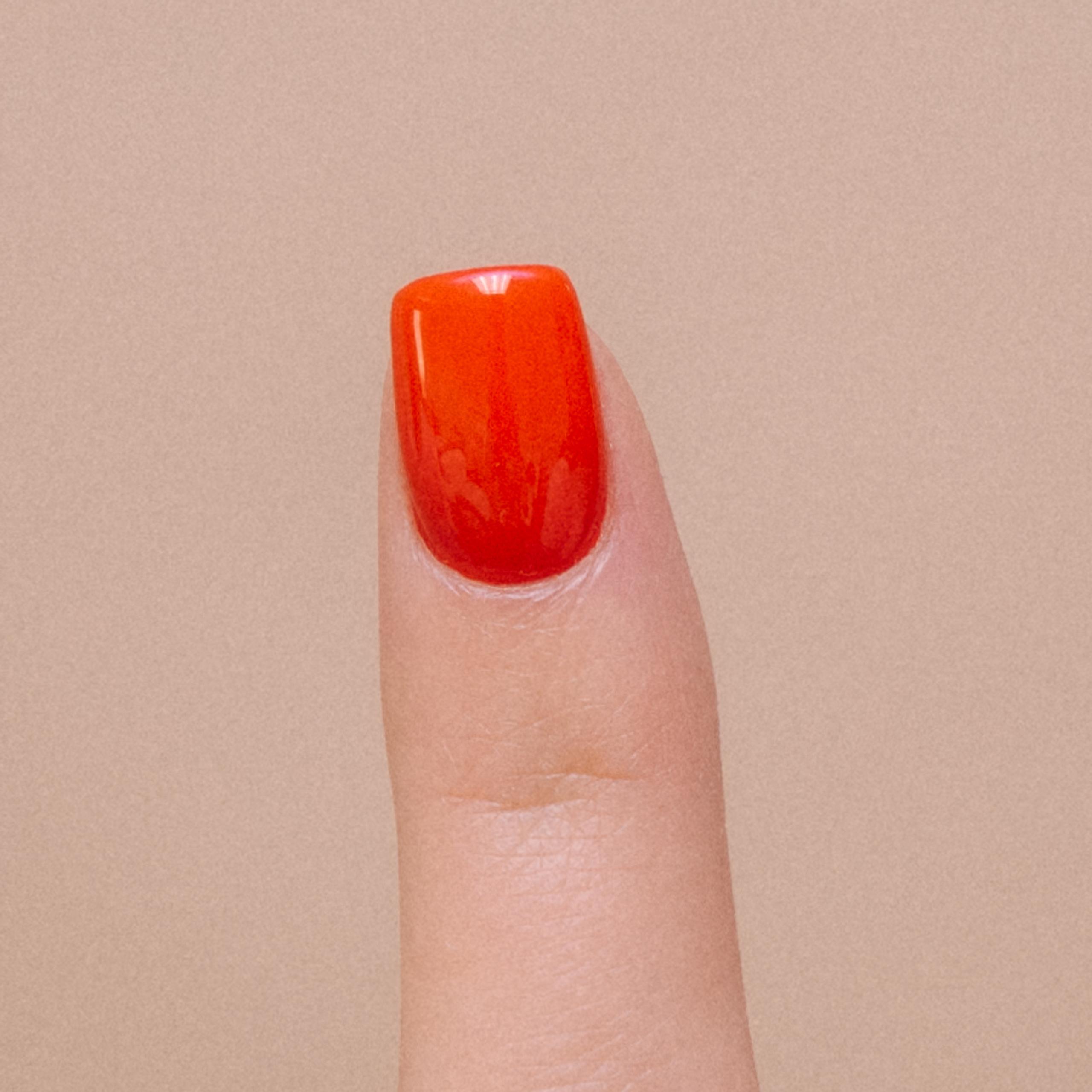 Finger pointing up with freshly painted red nail polish.