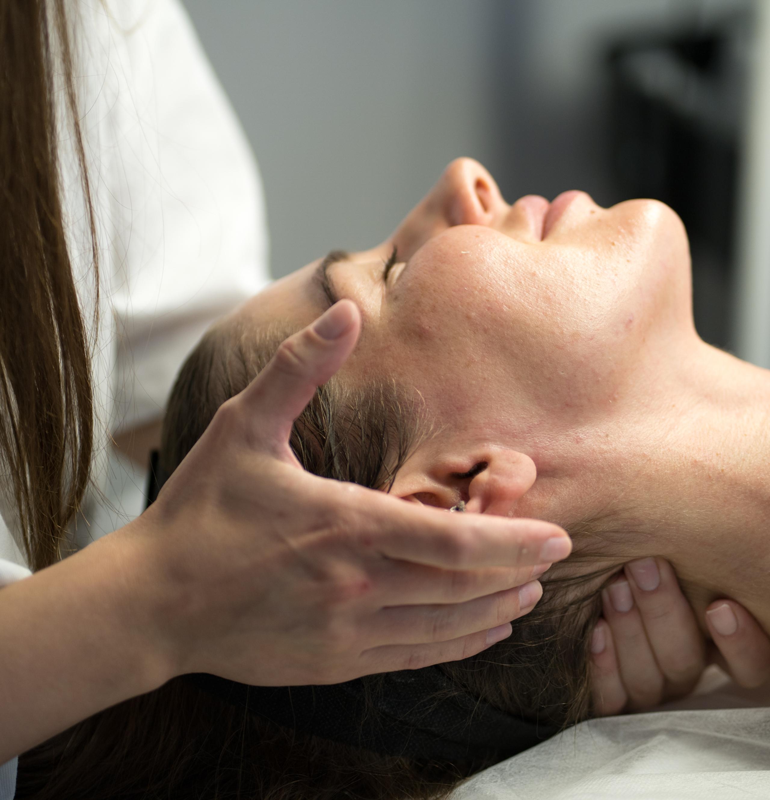 A person's hands massaging another person's neck and head.