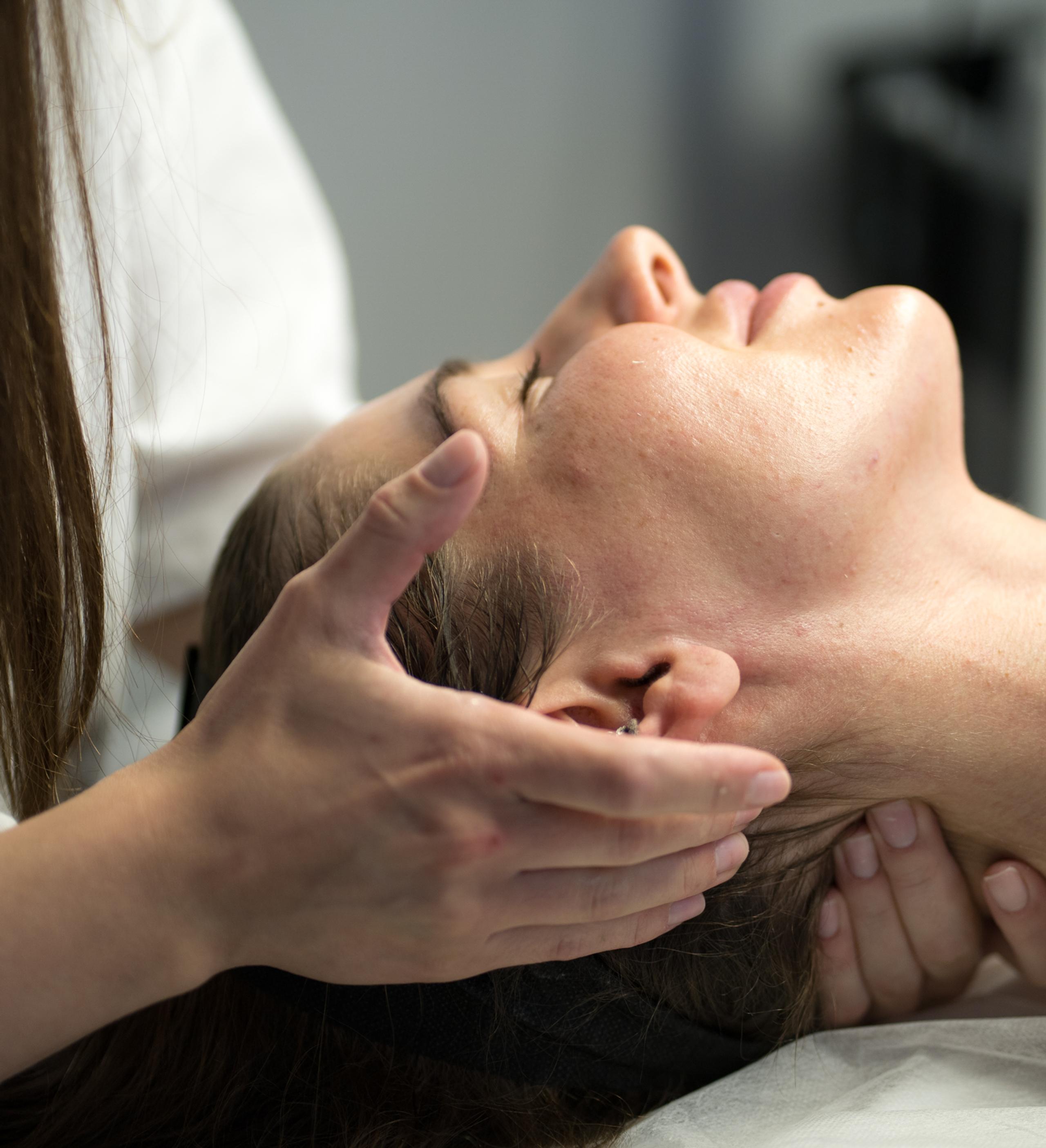 A person's hands massaging another person's neck and head.