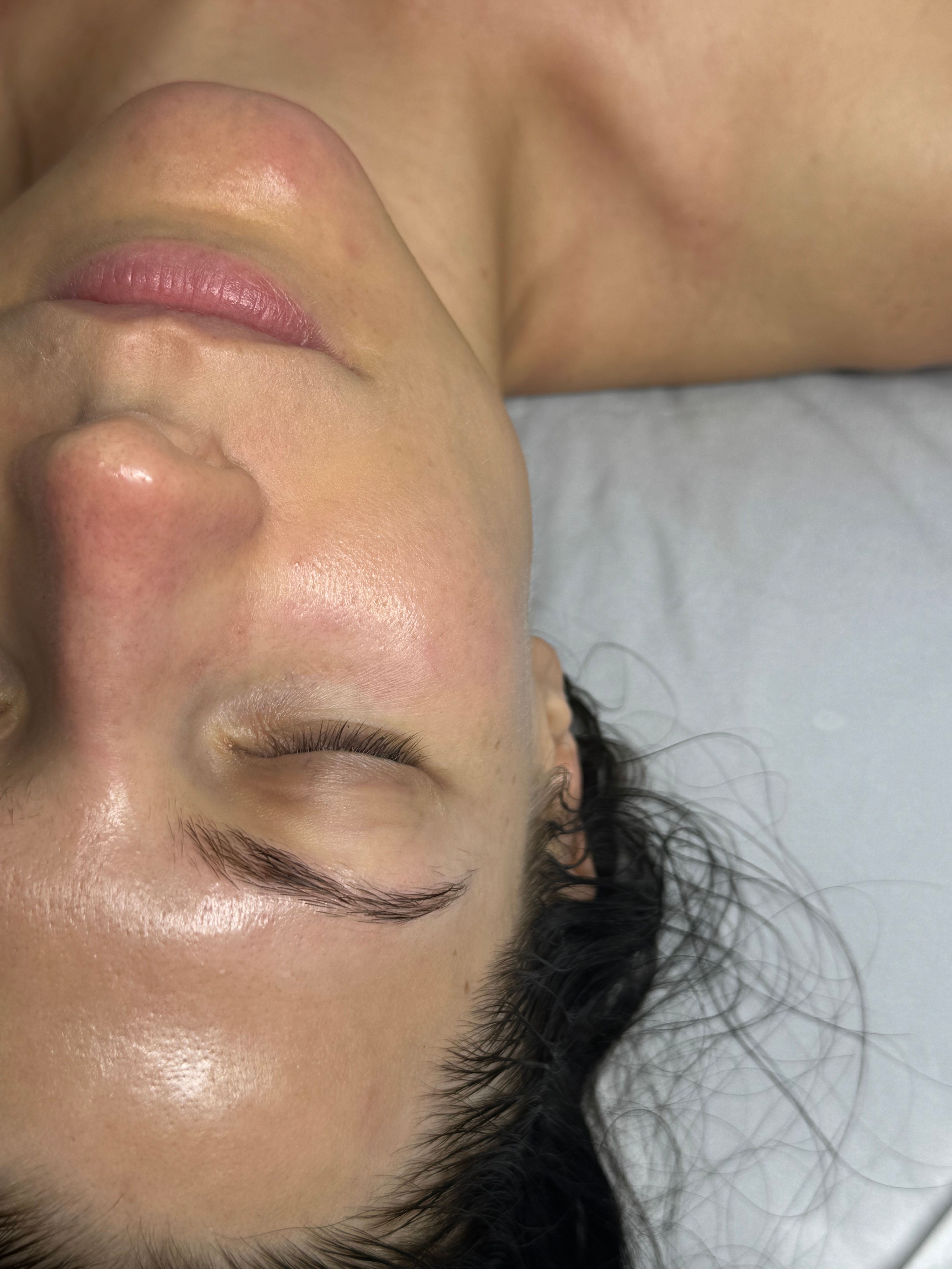 Close-up of a person's face with eyes closed, showing smooth, glowing skin.