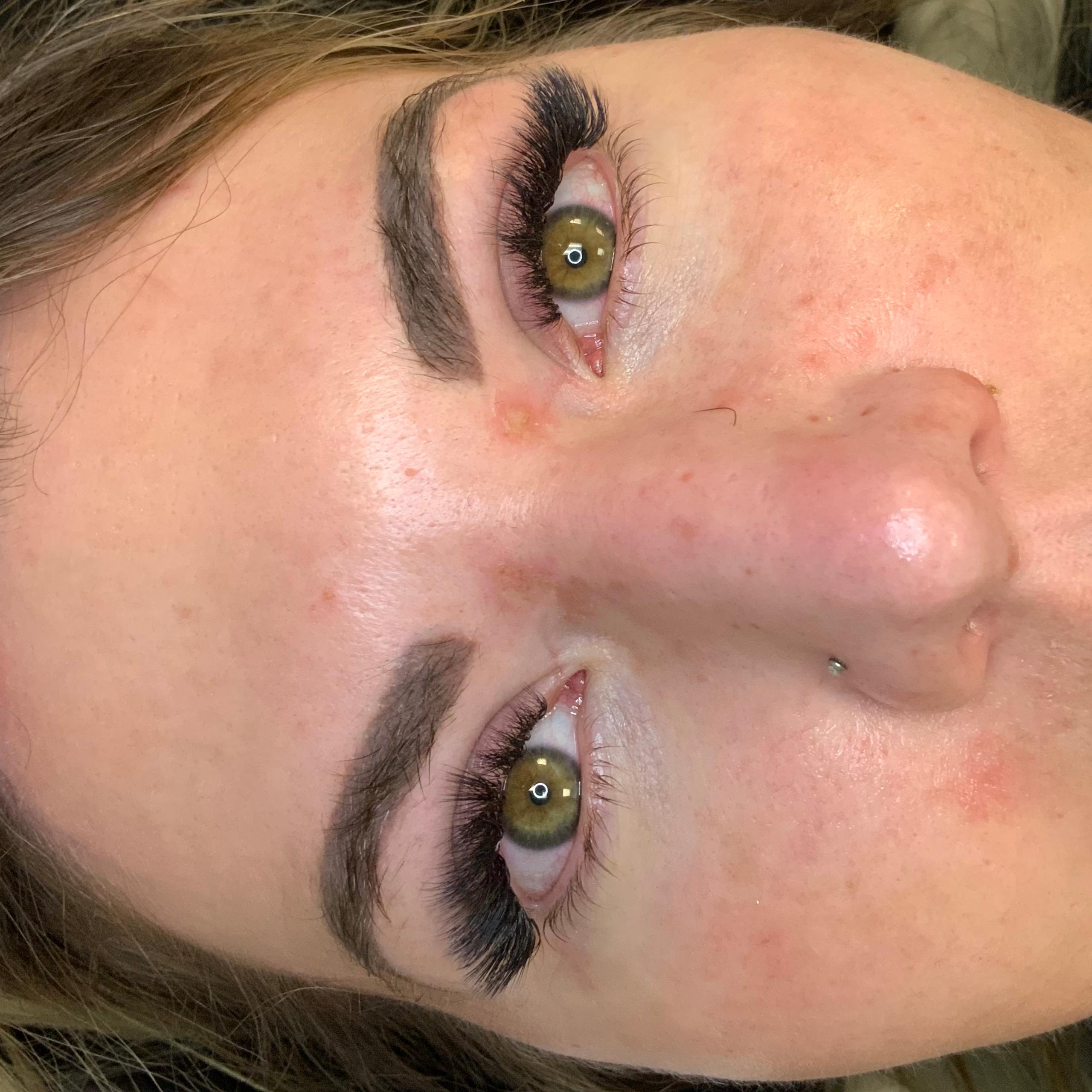 A woman lying down with dramatic eyelash extensions and green eyes