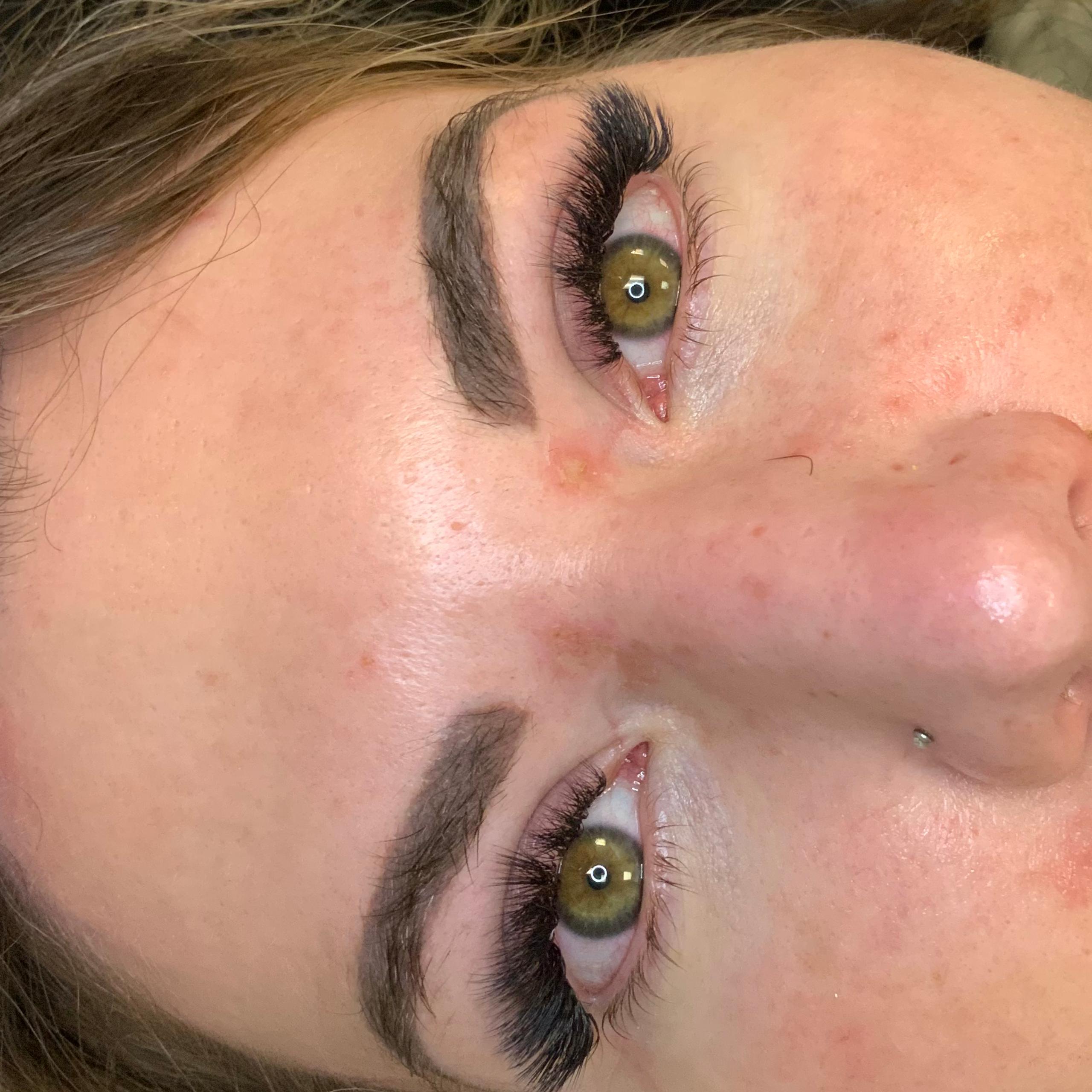 A woman lying down with dramatic eyelash extensions and green eyes