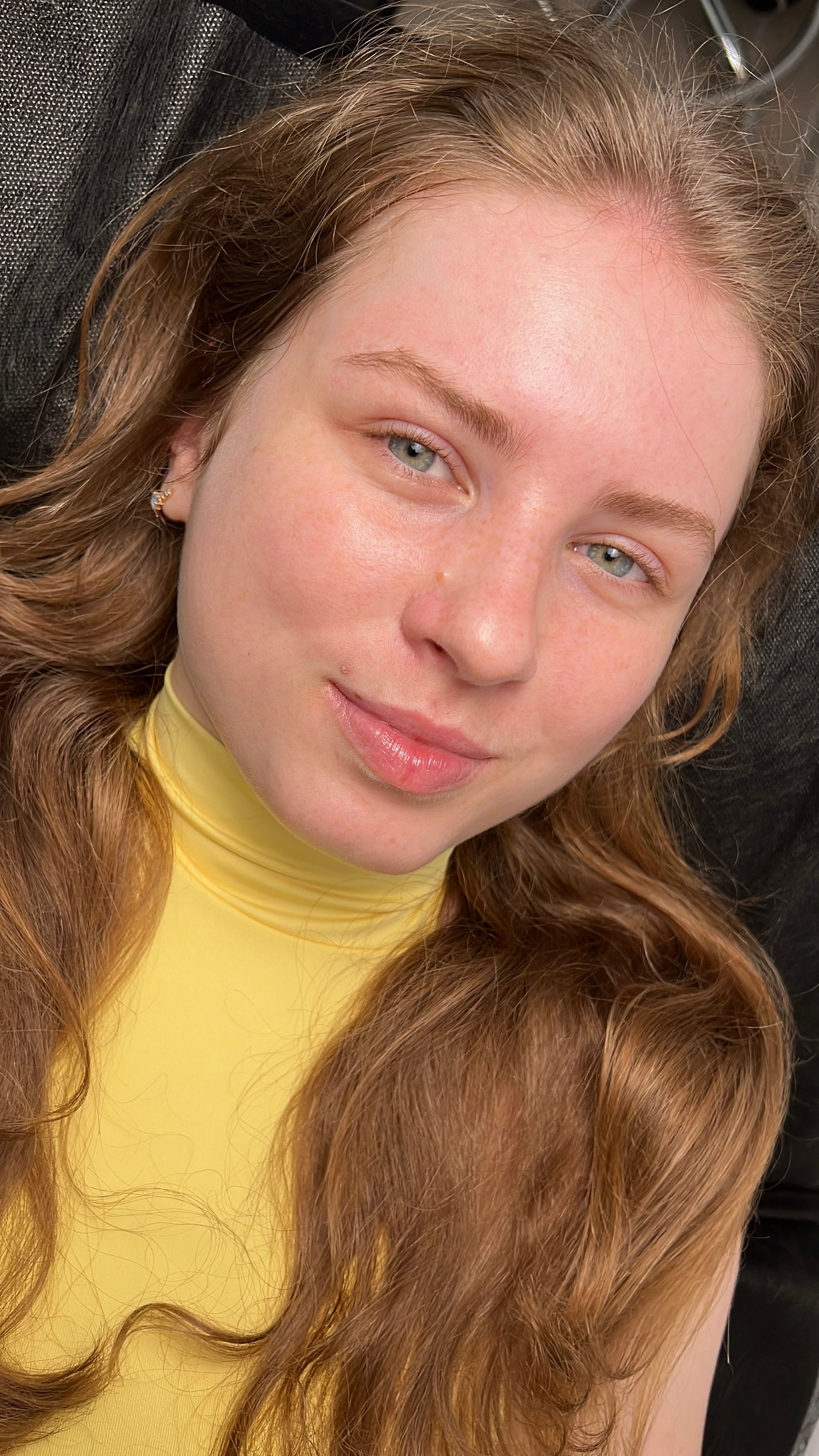 A woman with green eyes and long, light eyelashes lying down