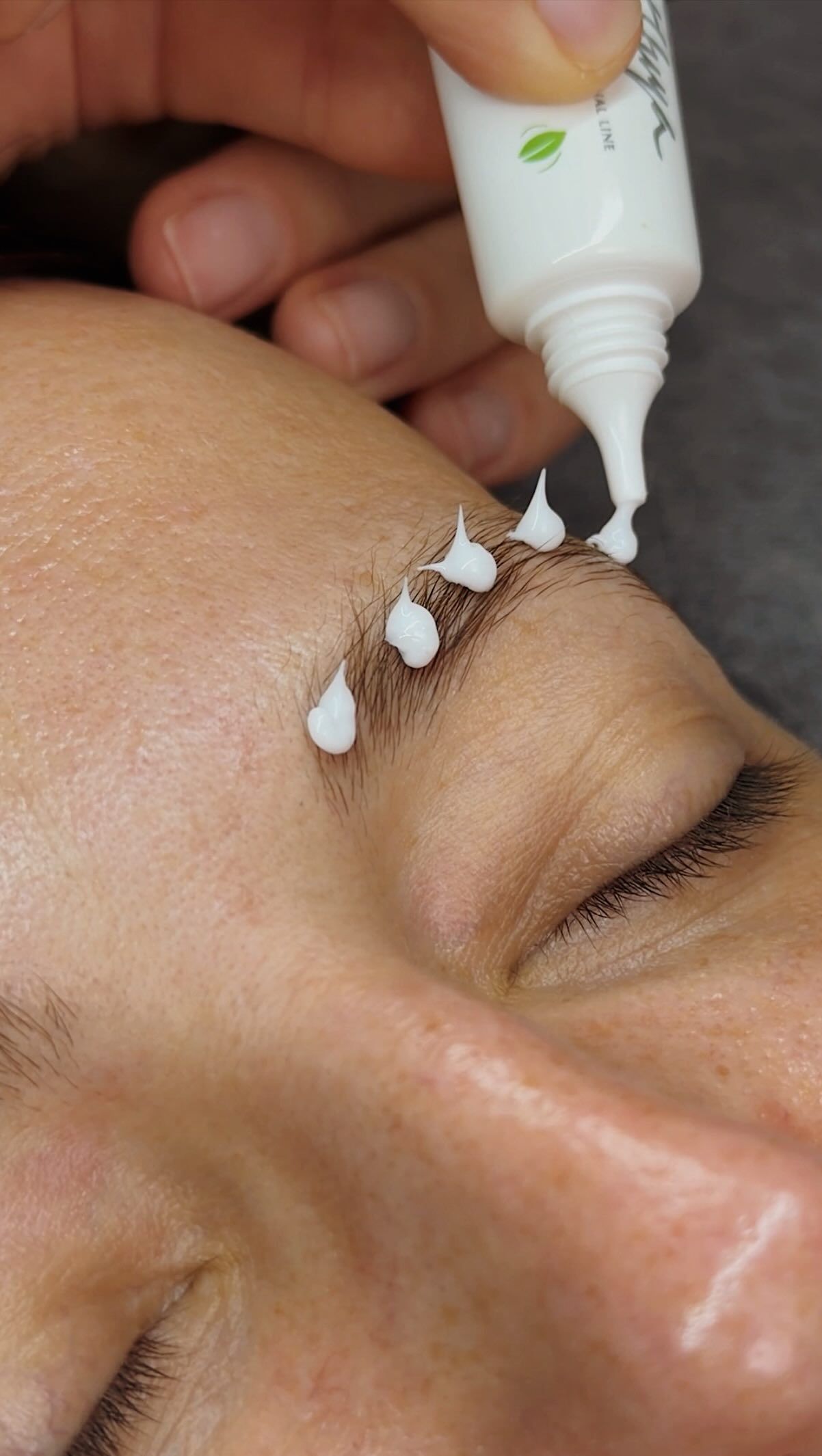 Brow lamination solution is applied to a client's eyebrow during treatment.