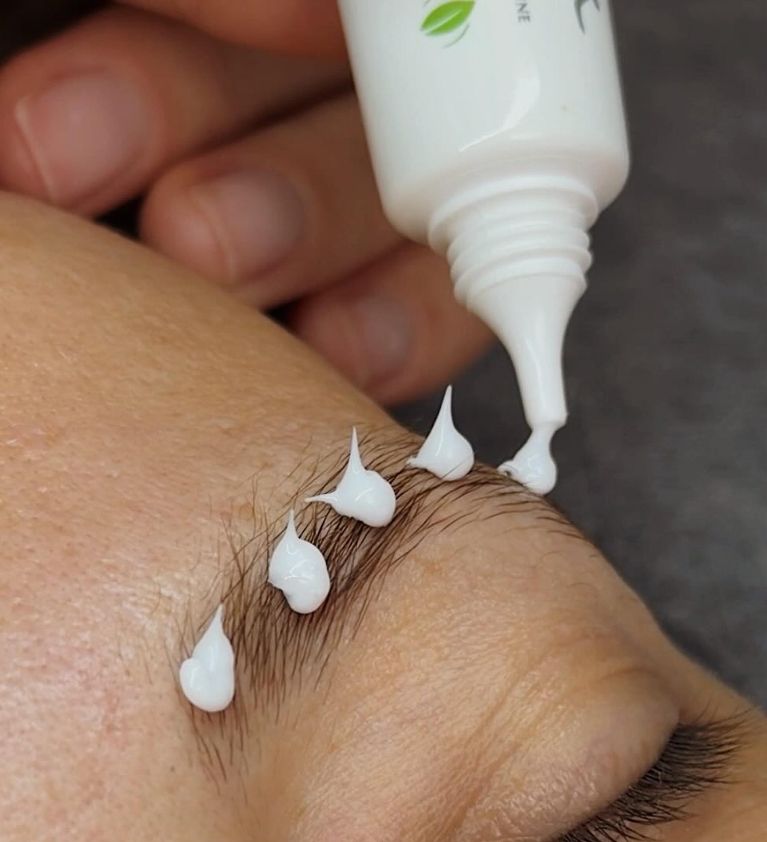 Brow lamination solution is applied to a client's eyebrow during treatment.