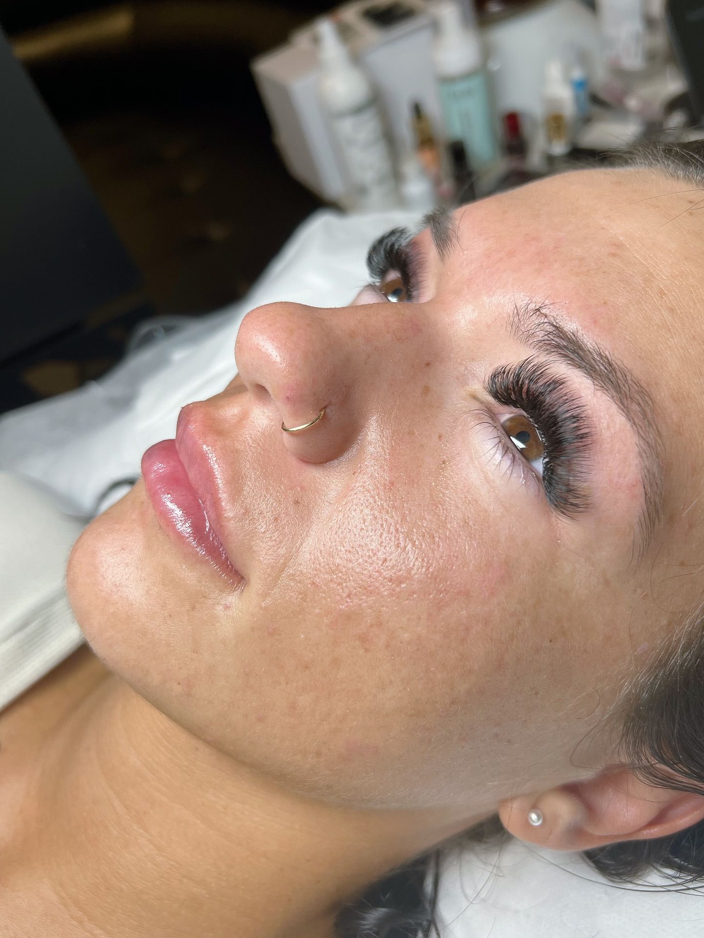 a woman laying on a treatment bed with her eyes open, showing mega volume lash extensions