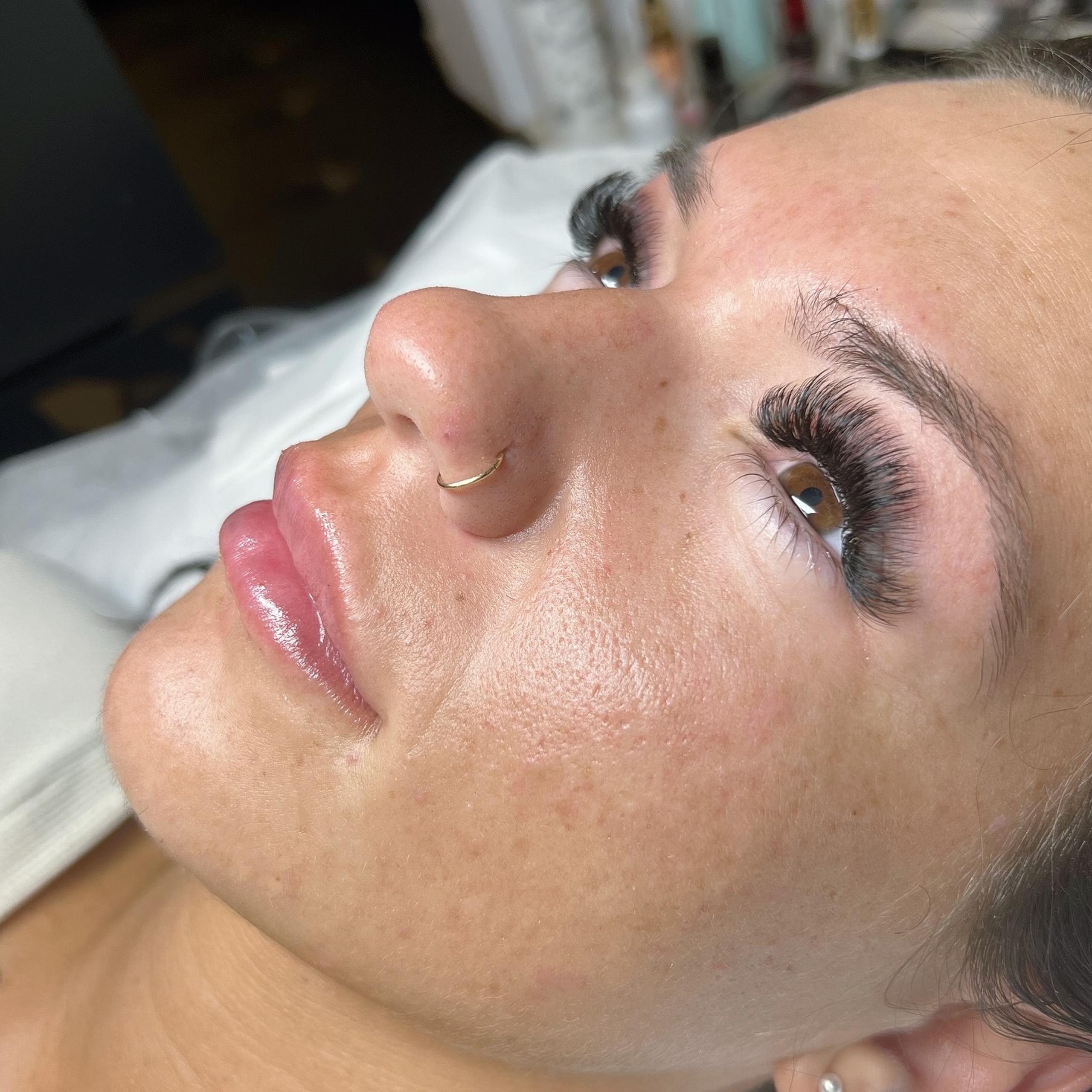 a woman laying on a treatment bed with her eyes open, showing mega volume lash extensions