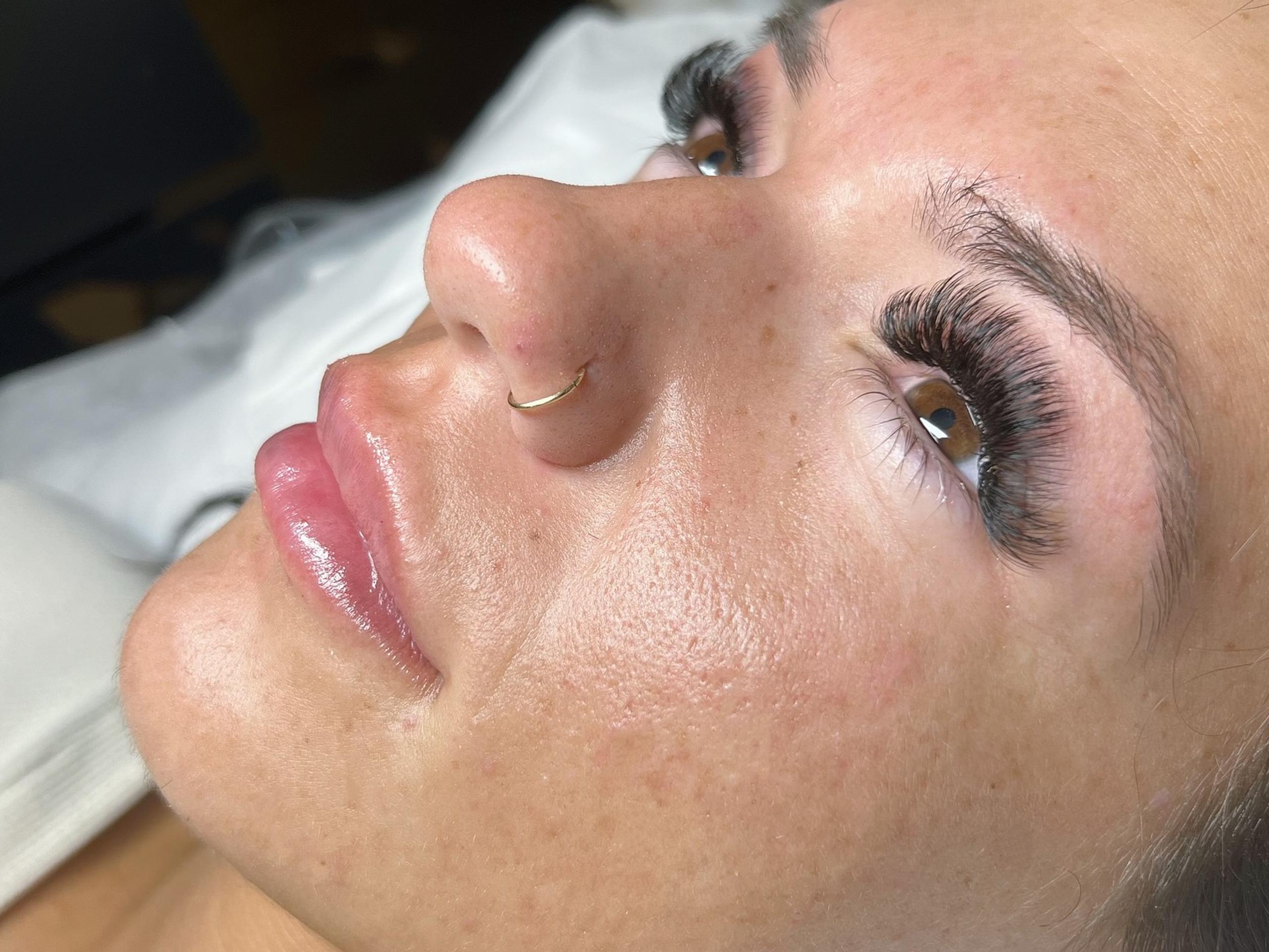 a woman laying on a treatment bed with her eyes open, showing mega volume lash extensions