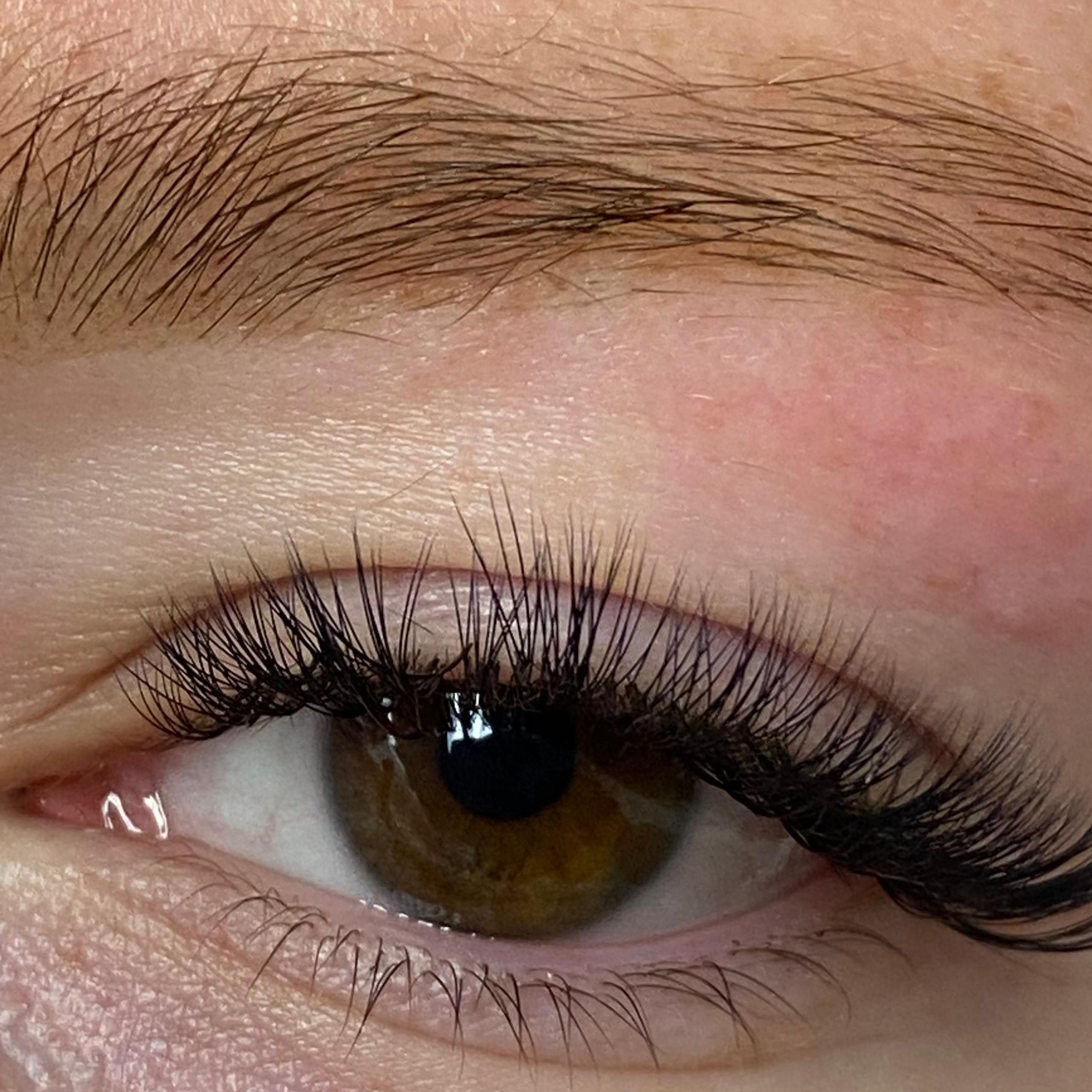 Close-up of a brown eye with voluminous eyelash extensions and a white eye patch underneath.