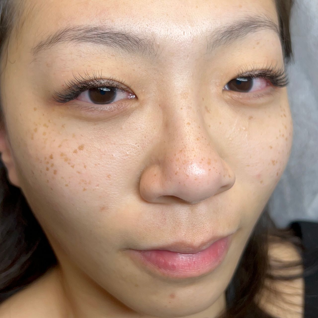 Close-up of a woman's face with long eyelashes and freckles.