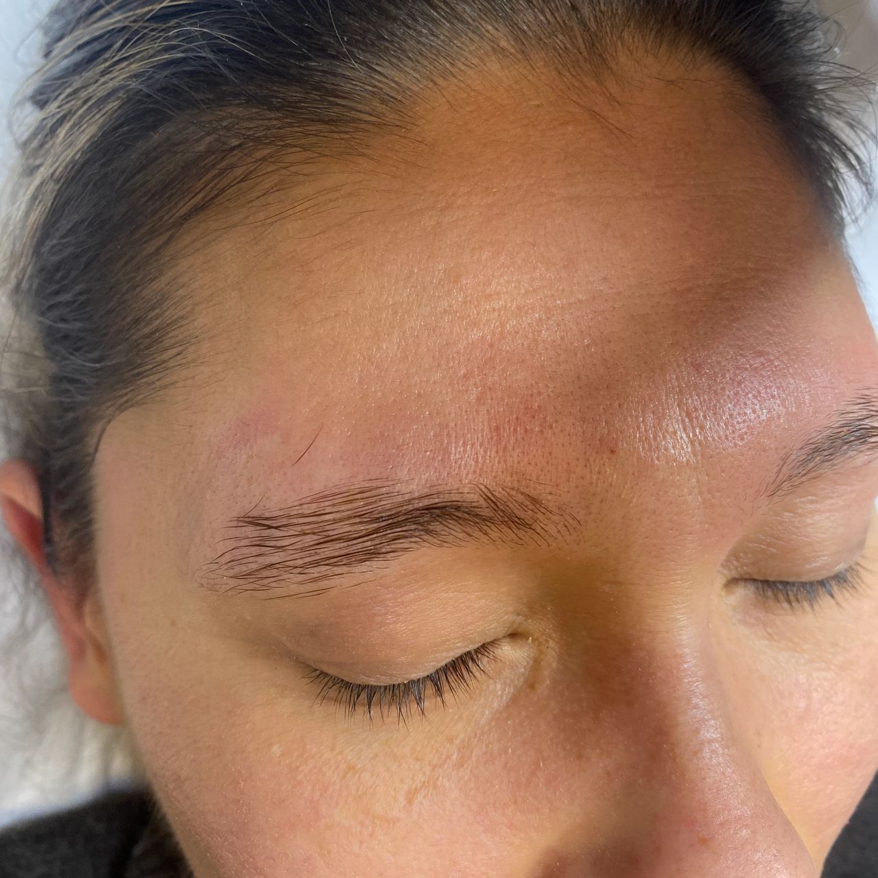 Close-up of a person's face with closed eyes, showing an upward-brushed eyebrow