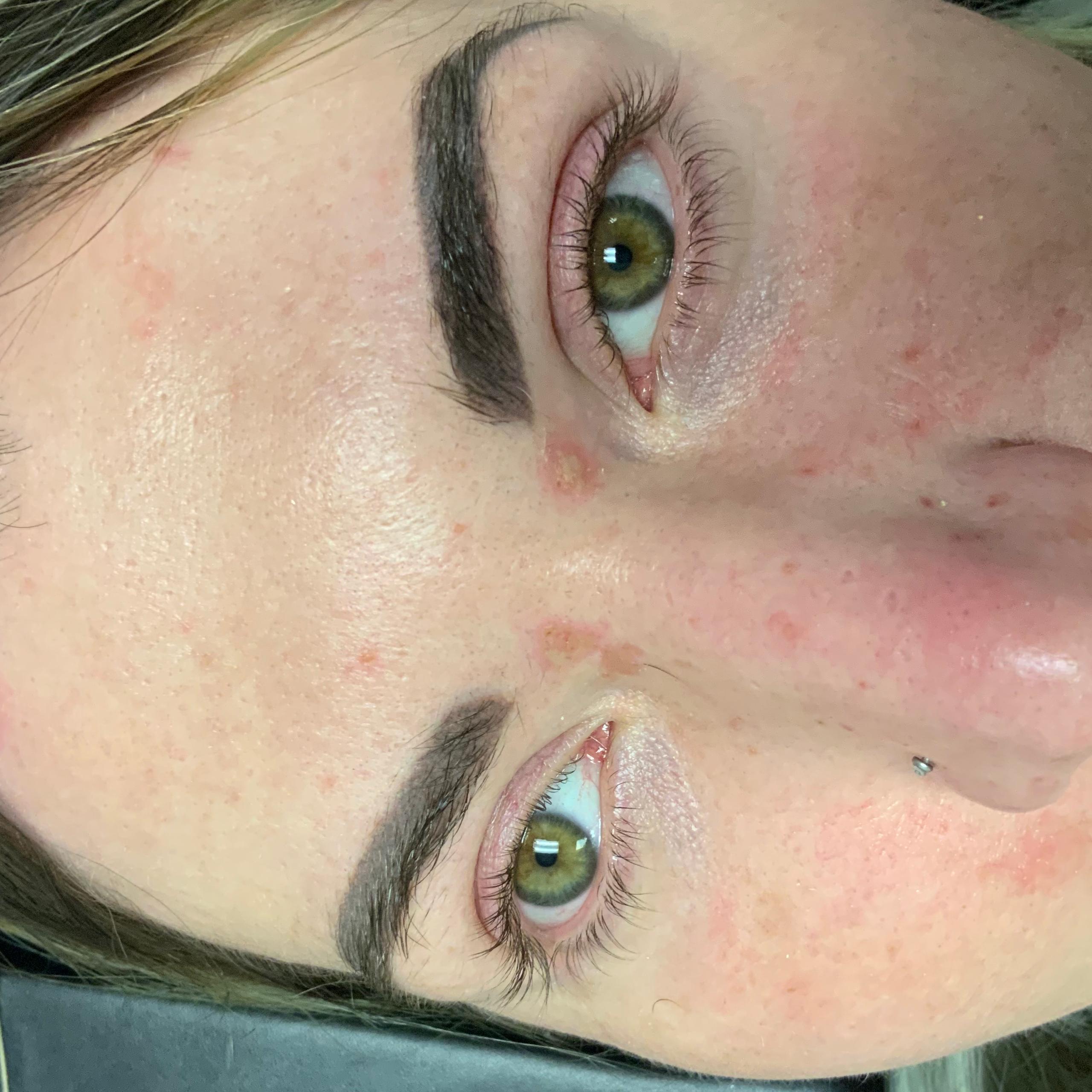 Aperson's face with green eyes and dark eyebrows