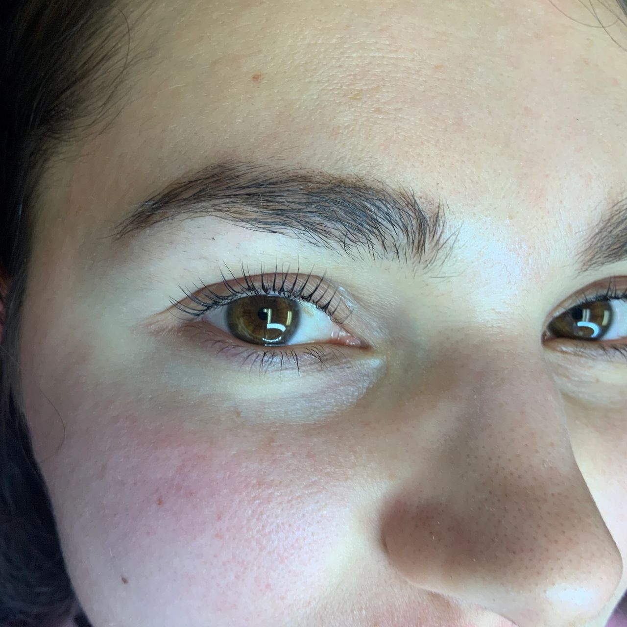 Close-up of a person's face with brown eyes and long eyelashes.